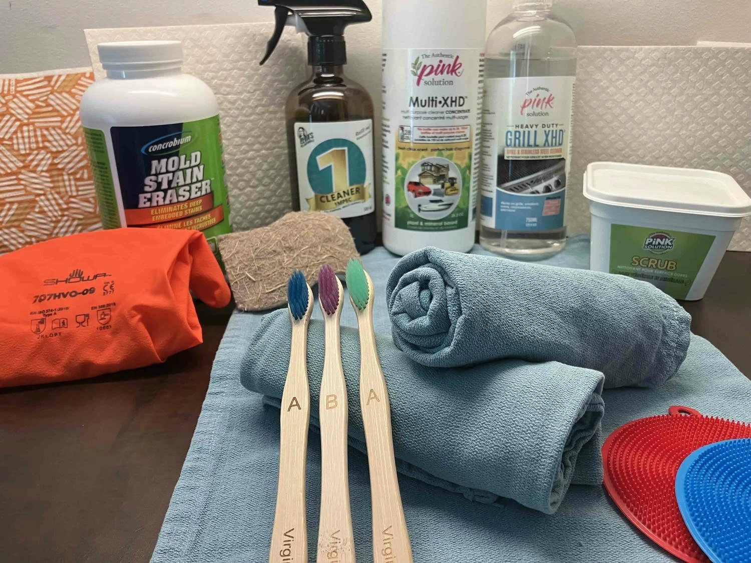 A selection of cleaning products, cloths, brushes, and scrubbers.