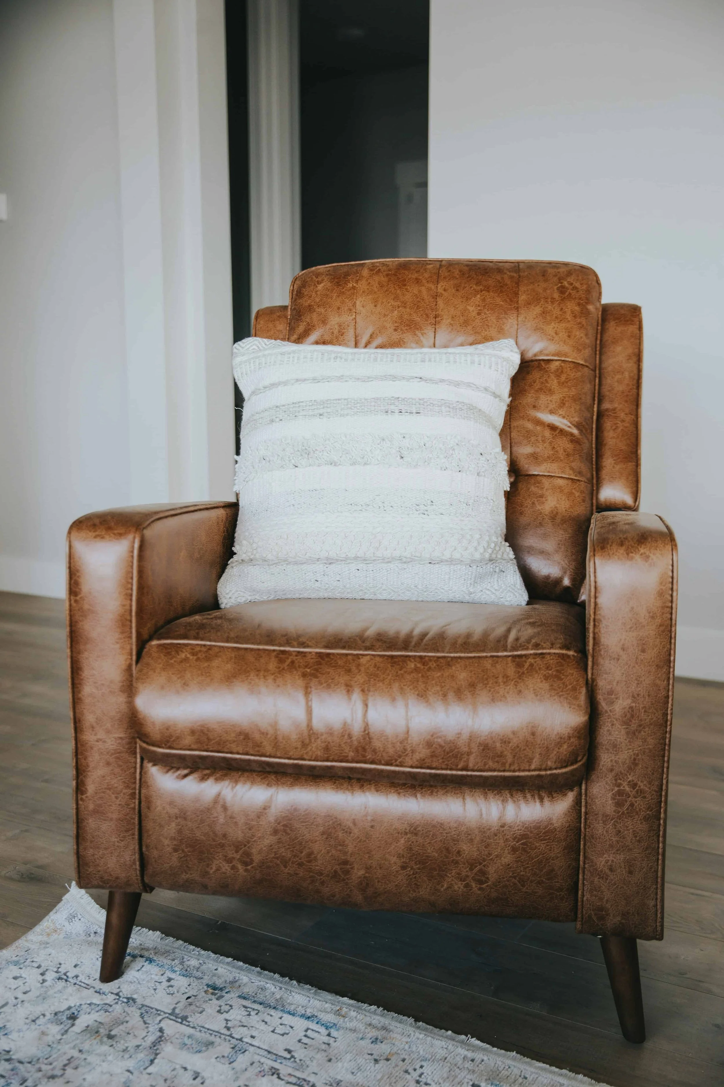 A brown leather chair with a white cushion