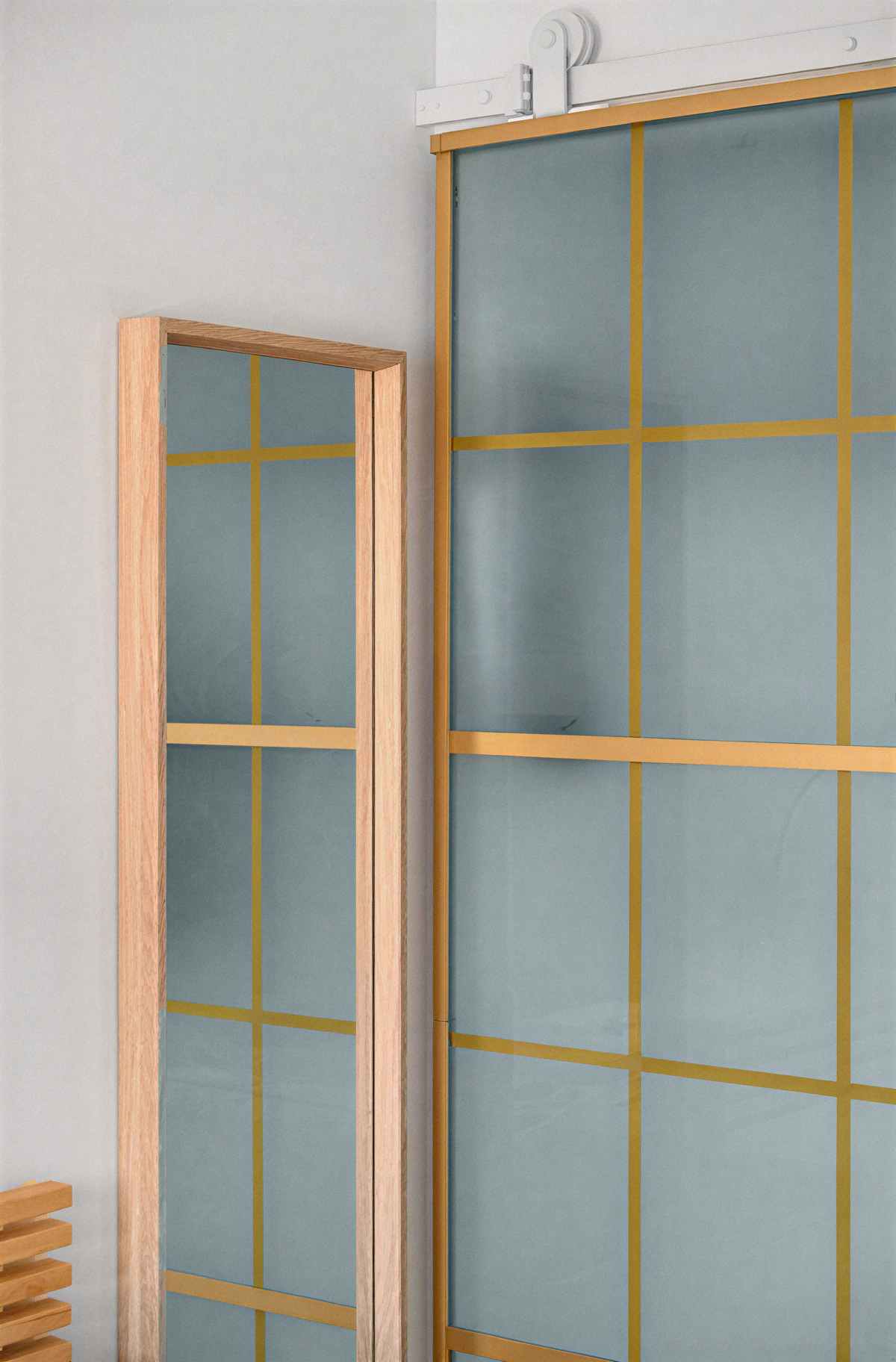 Porte coulissante en verre translucide à trame dorée séparant la chambre du reste de l’appartement à Ouistreham.