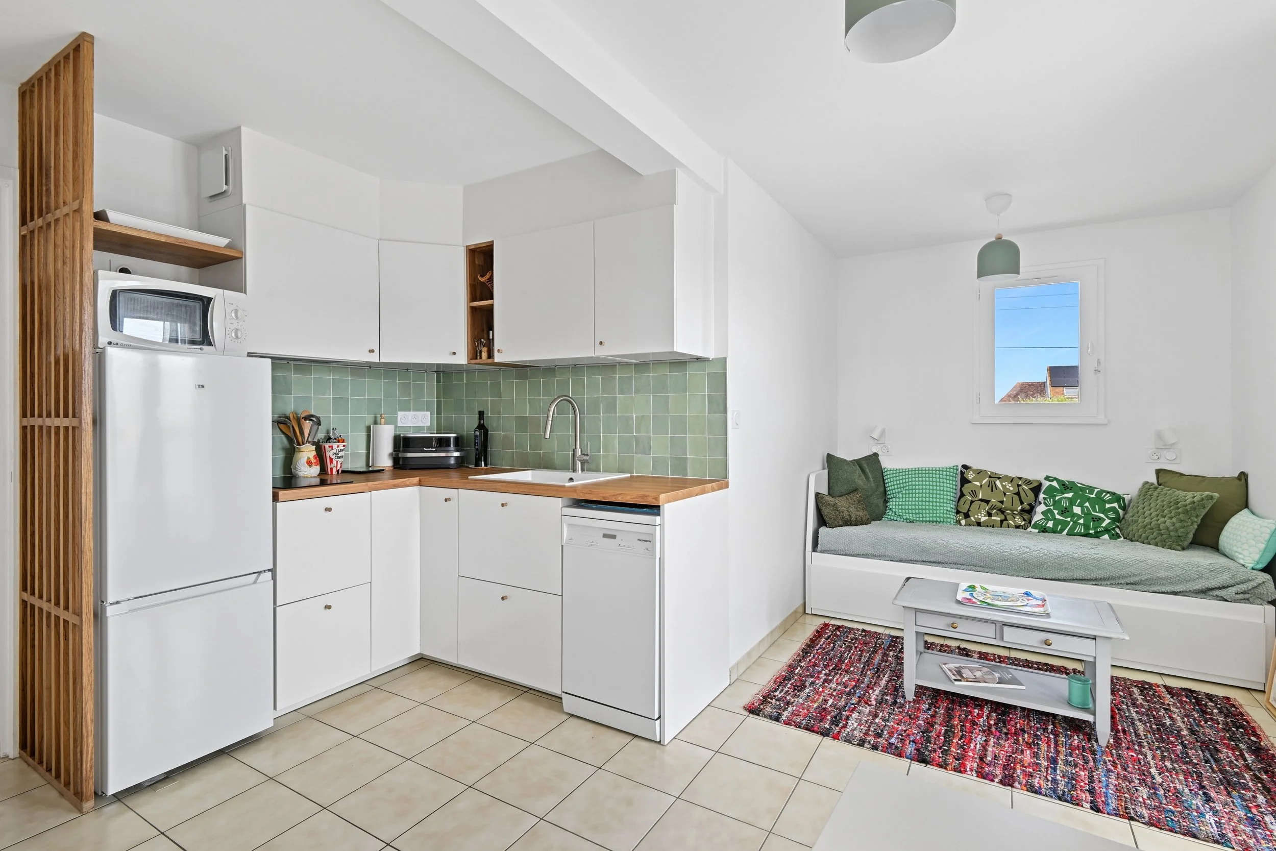 Vue d’ensemble de la cuisine ouverte sur le séjour après rénovation de cet appartement de 30 m² à Ouistreham.