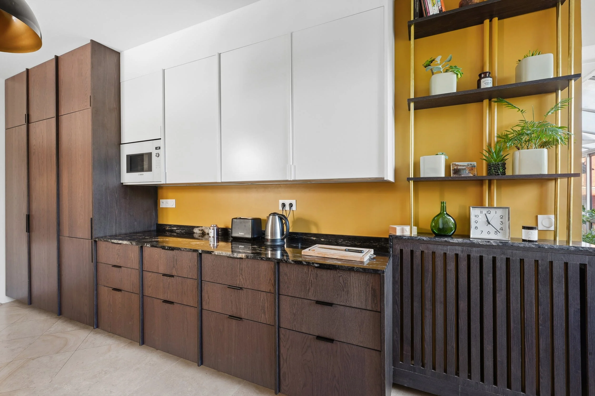 Agencement de cuisine sur mesure associant placards blancs, façades en bois de type noyer et plan de travail en granit noir.