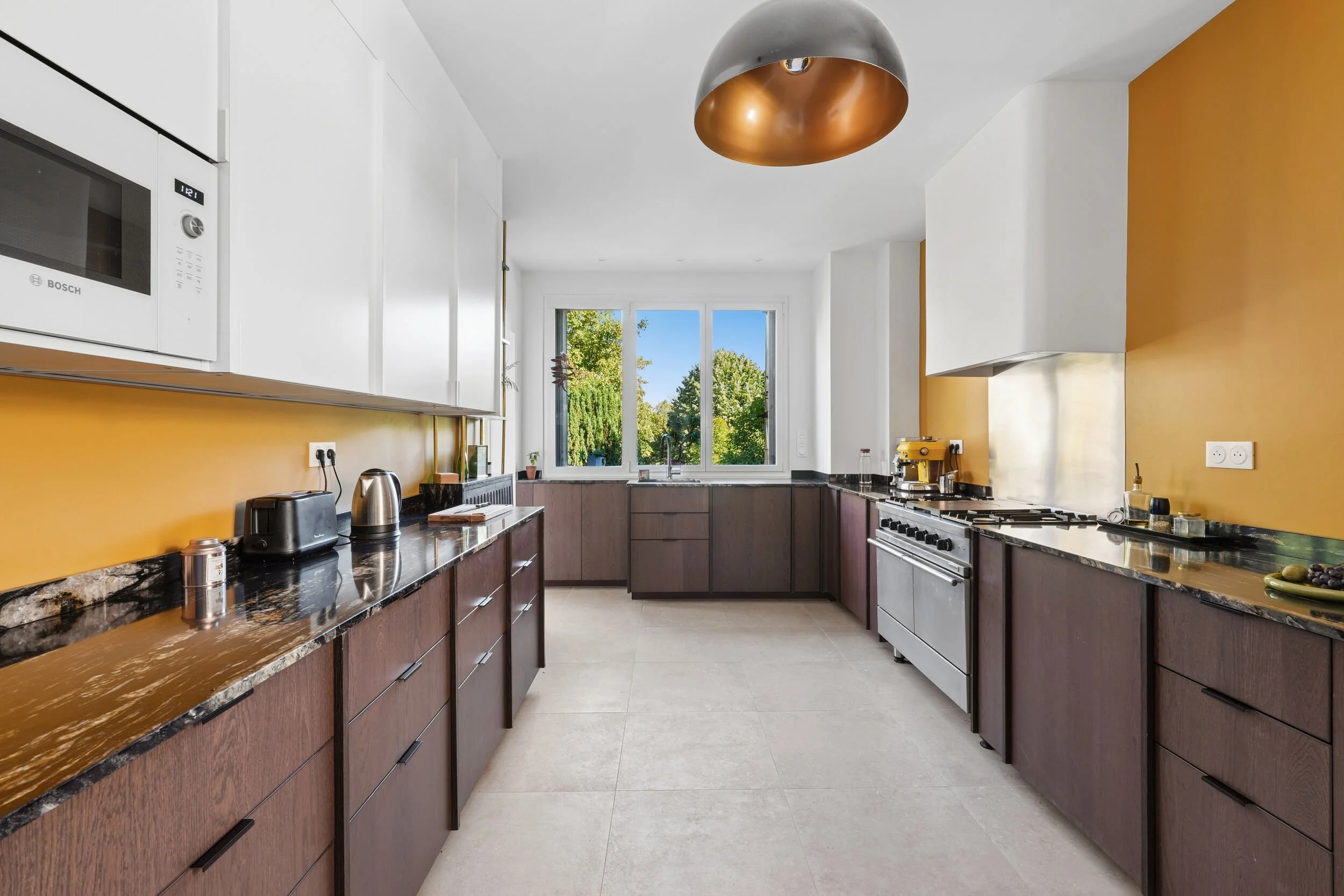 Rénovation d'une cuisine spacieuse à Colombes avec nombreux rangements, électroménager intégré et plans de travail en granit.