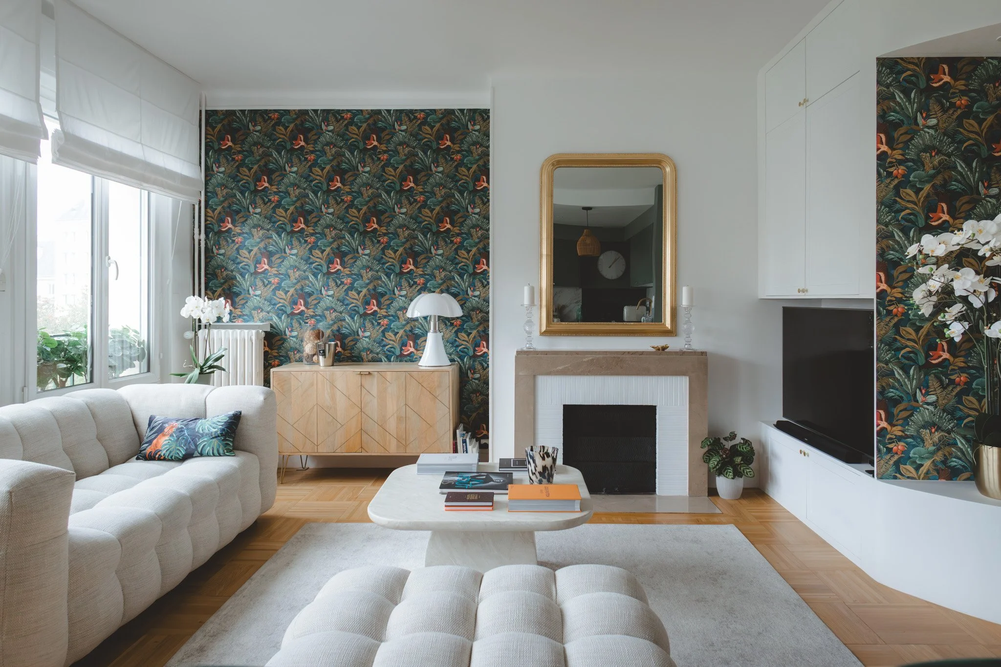 Salon lumineux avec menuiserie sur mesure, banquette bois et papier peint panoramique végétal. Un espace chaleureux et personnalisé dans cet appartement rénové à Caen.