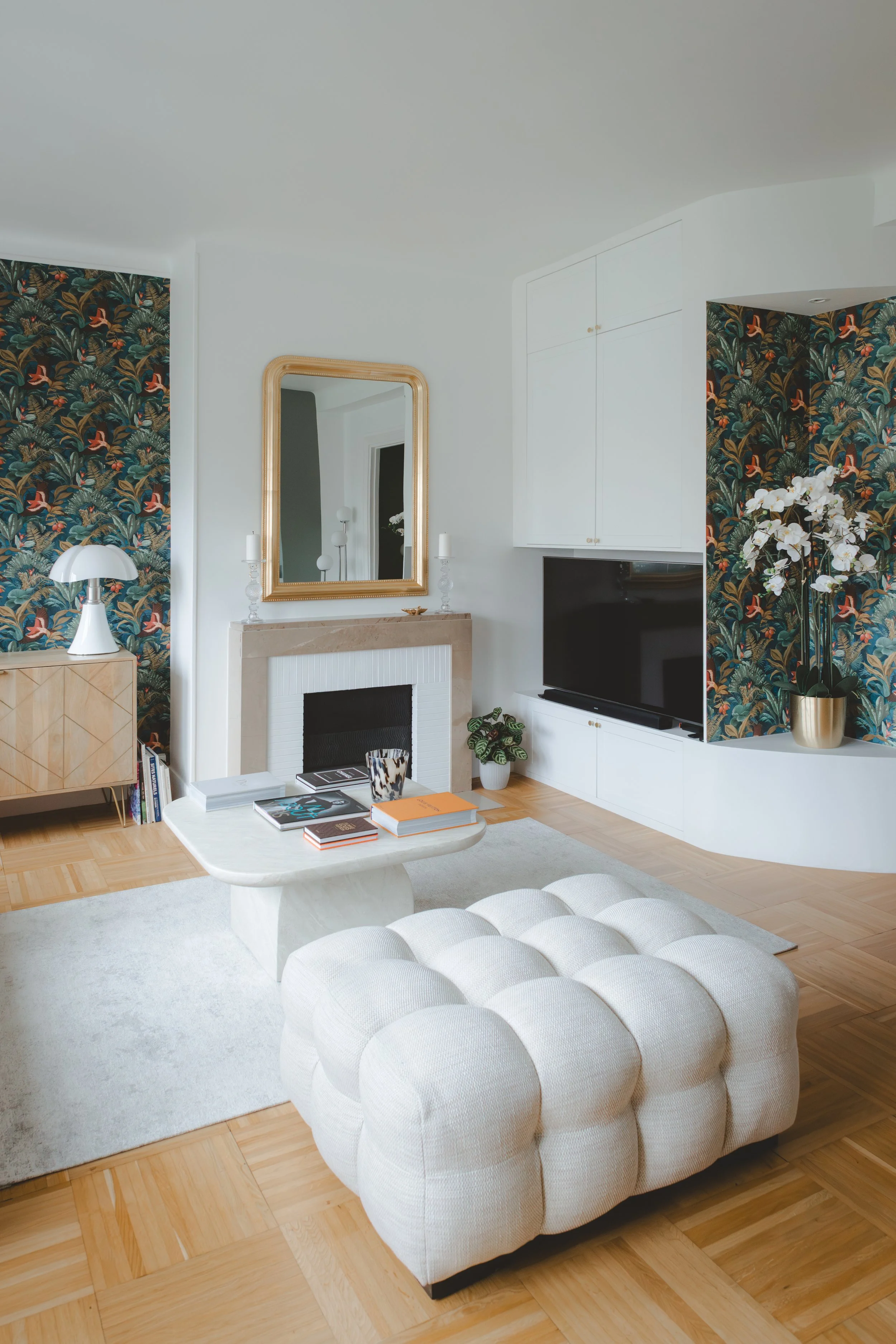 Salon lumineux avec menuiserie sur mesure, banquette bois et papier peint panoramique végétal. Un espace chaleureux et personnalisé dans cet appartement rénové à Caen.