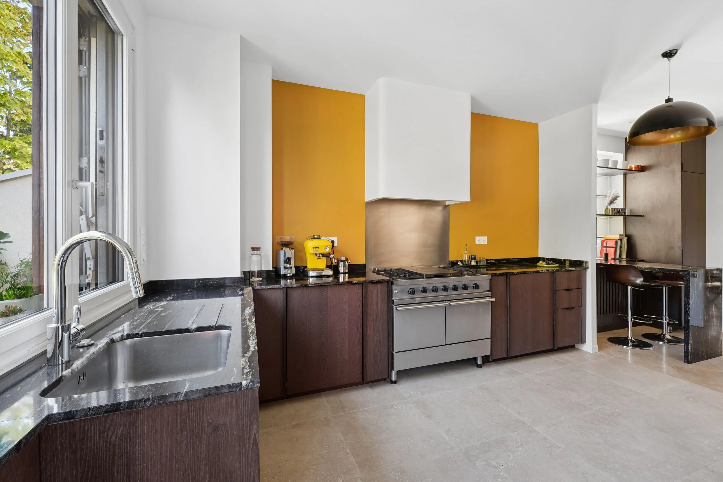 Cuisine rénovée à Colombes avec grande cuisinière, mobilier en bois foncé et coin repas aménagé à proximité.
