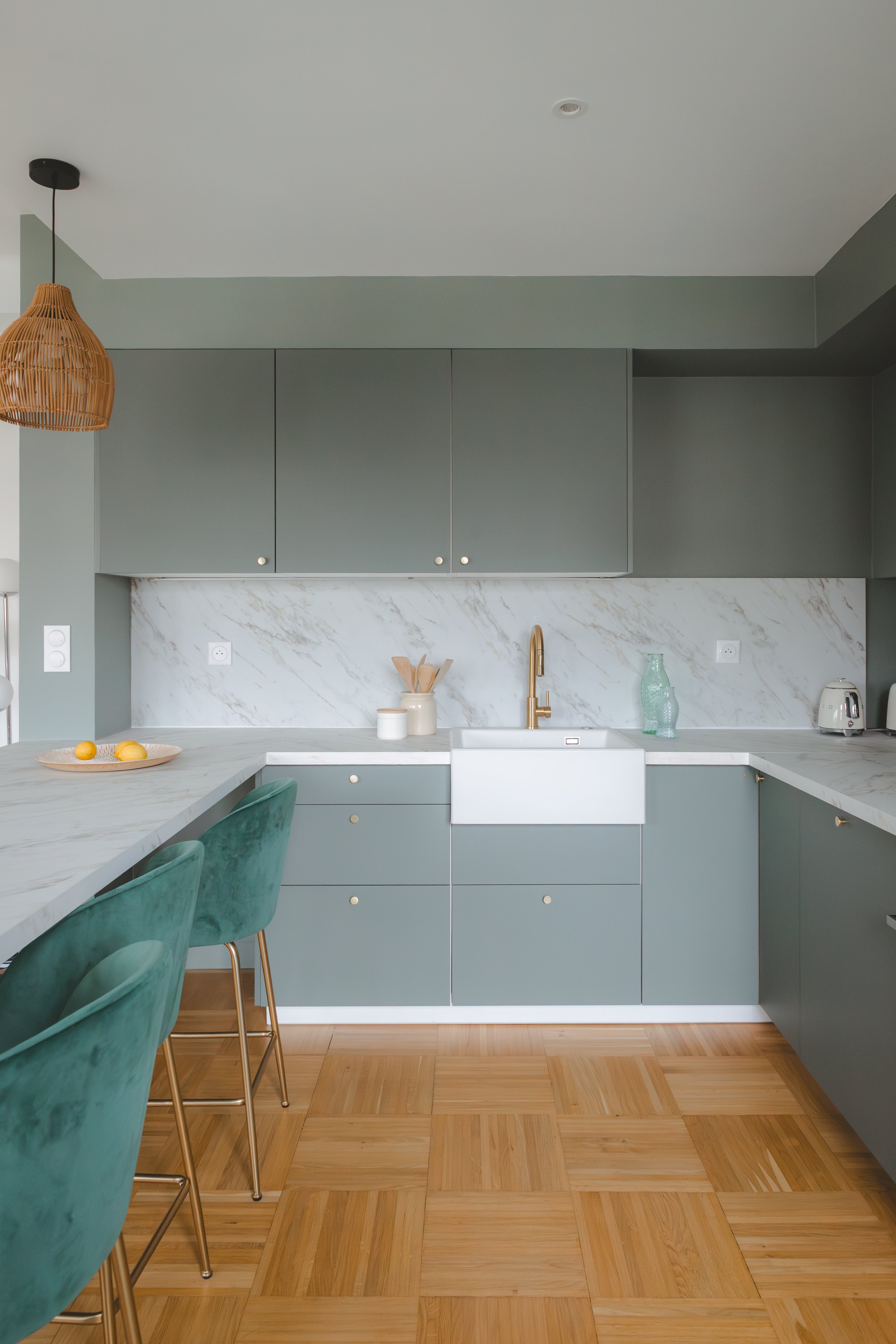 Cuisine ouverte contemporaine à Caen, avec façades vertes mates, plan de travail effet marbre et évier timbre d'office. 
Un projet signé RIVABEL mêlant fonctionnalité et esthétique dans un appartement du centre de Caen.