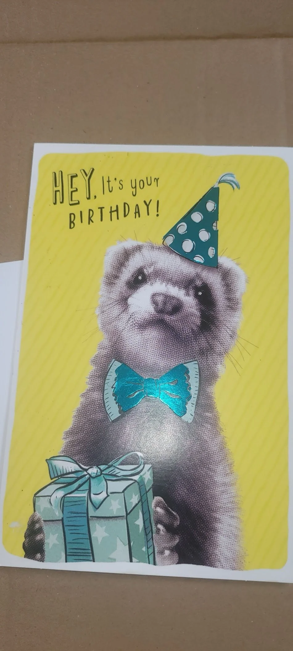 A birthday card featuring a cute otter holding a wrapped birthday present, wearing a blue bowtie and a party hat, with the text "HEY, it's your BIRTHDAY!" on a yellow background.