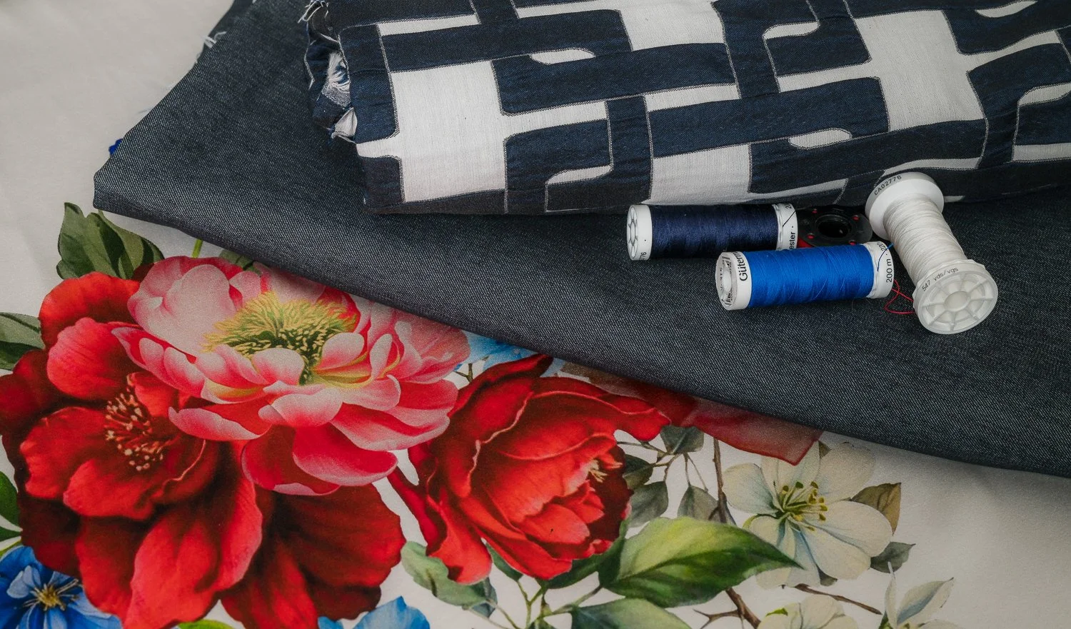 Stoffe, Garnspulen und Stoffreste, mit Blumen bedrucktes Papier