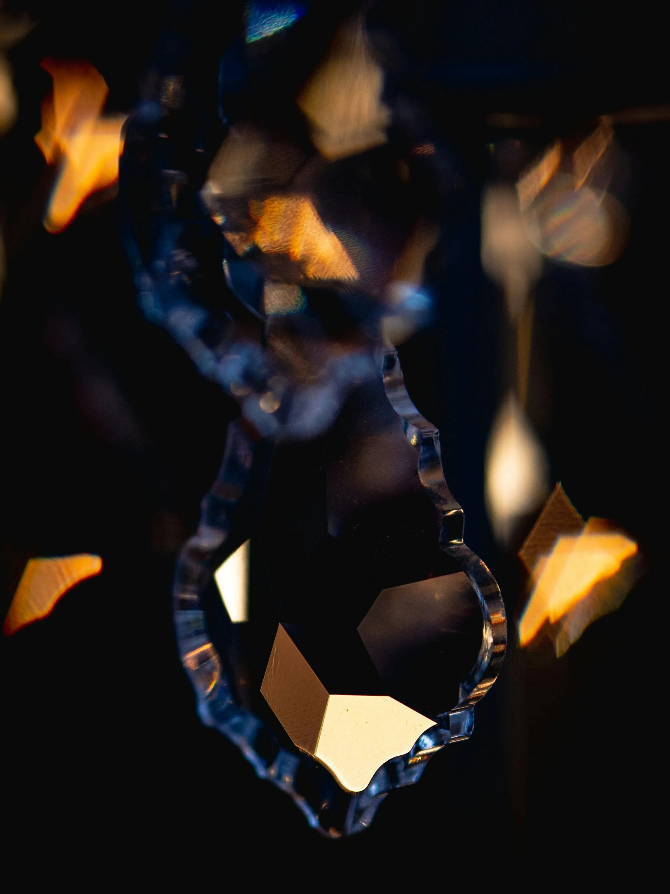 Close-up of a glittering, faceted crystal or gemstone reflecting light in dark background.