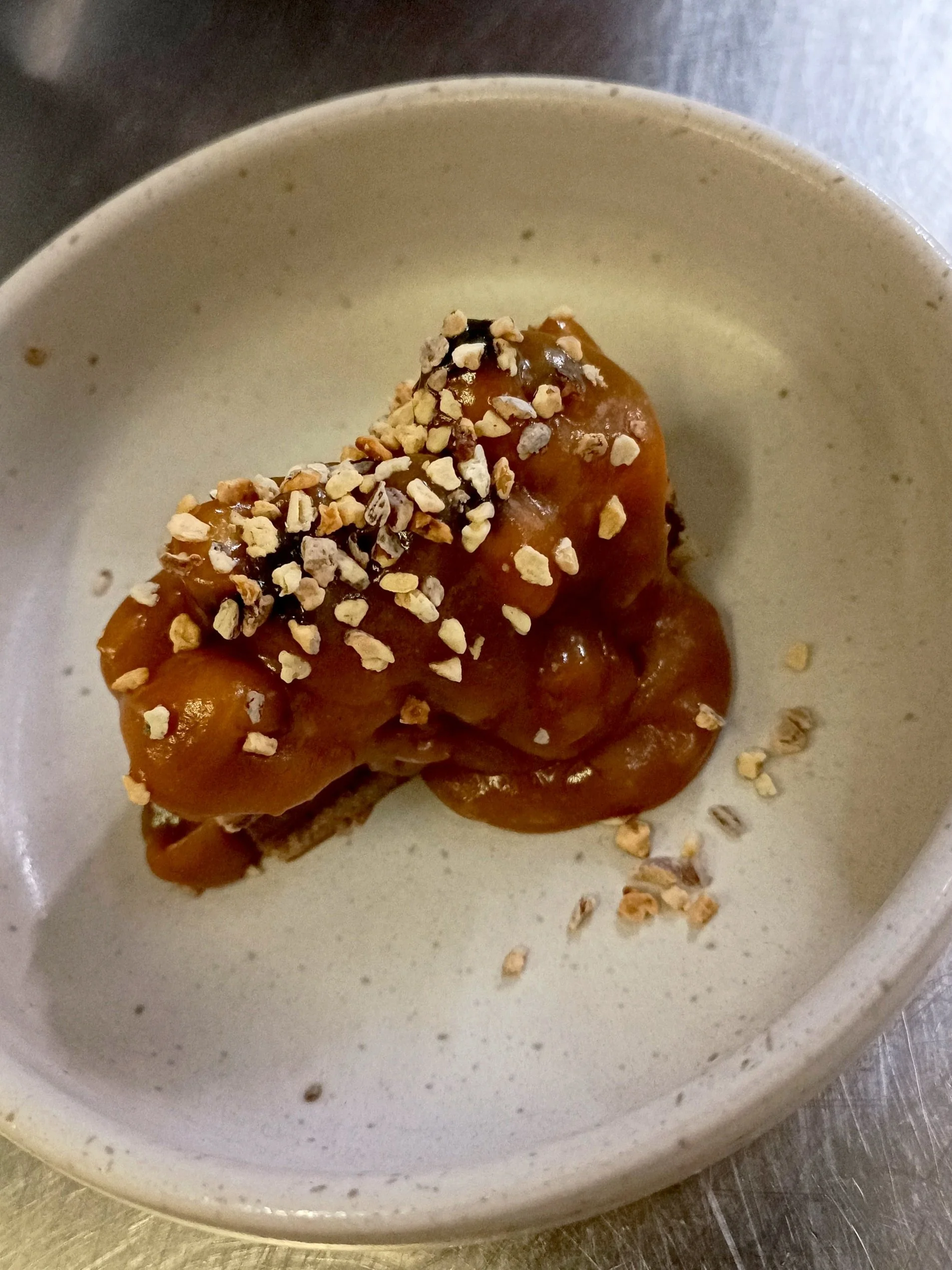 Dessert avec sauce caramel et éclats de noix dans une assiette blanche.