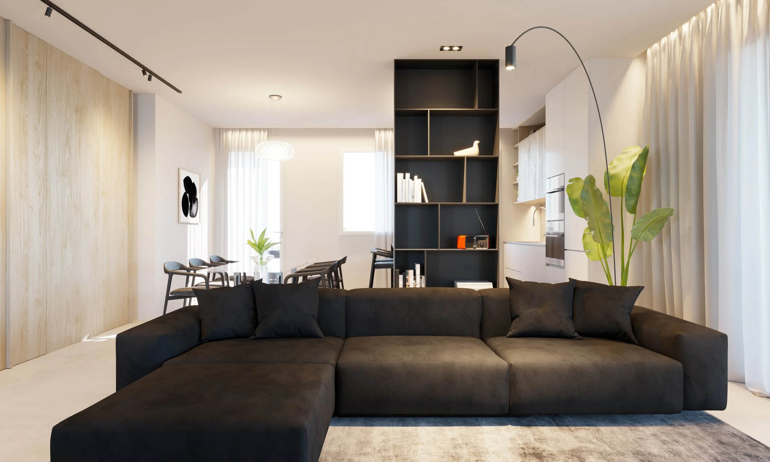 Soggiorno moderno con divano nero, scaffale nero con decorazioni e libri, cucina bianca con forno, e sala da pranzo con tavolo e sedie. Finestra con tende bianche e pianta grande vicino alla finestra.