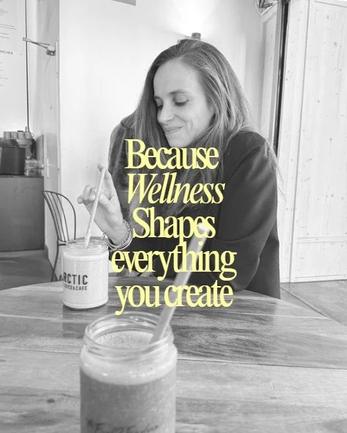 Une femme avec des cheveux longs assise à une table en bois, buvant dans un verre avec une paille. Il y a un autre verre devant elle. Le texte en jaune sur l'image dit : 'Parce que le bien-être façonne tout ce que vous créez'.