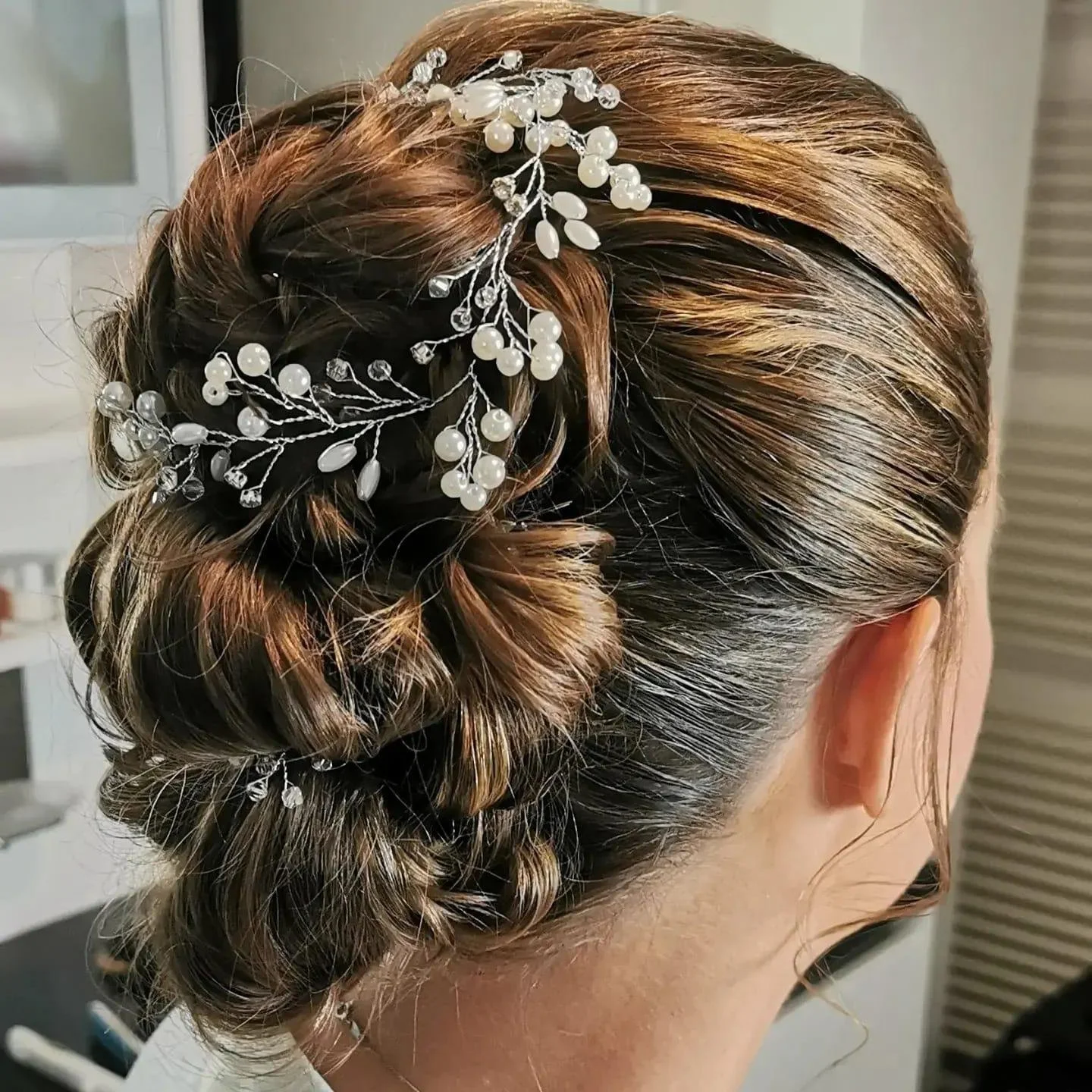 Intricate braided updo with decorative pearl hair accessory.