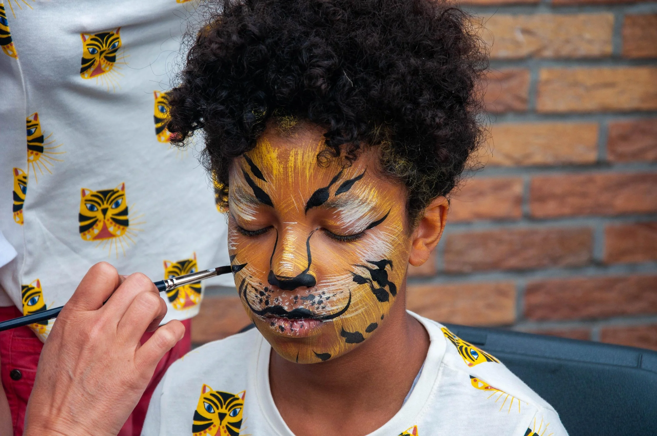 Child getting face painted like a tiger with vibrant colors