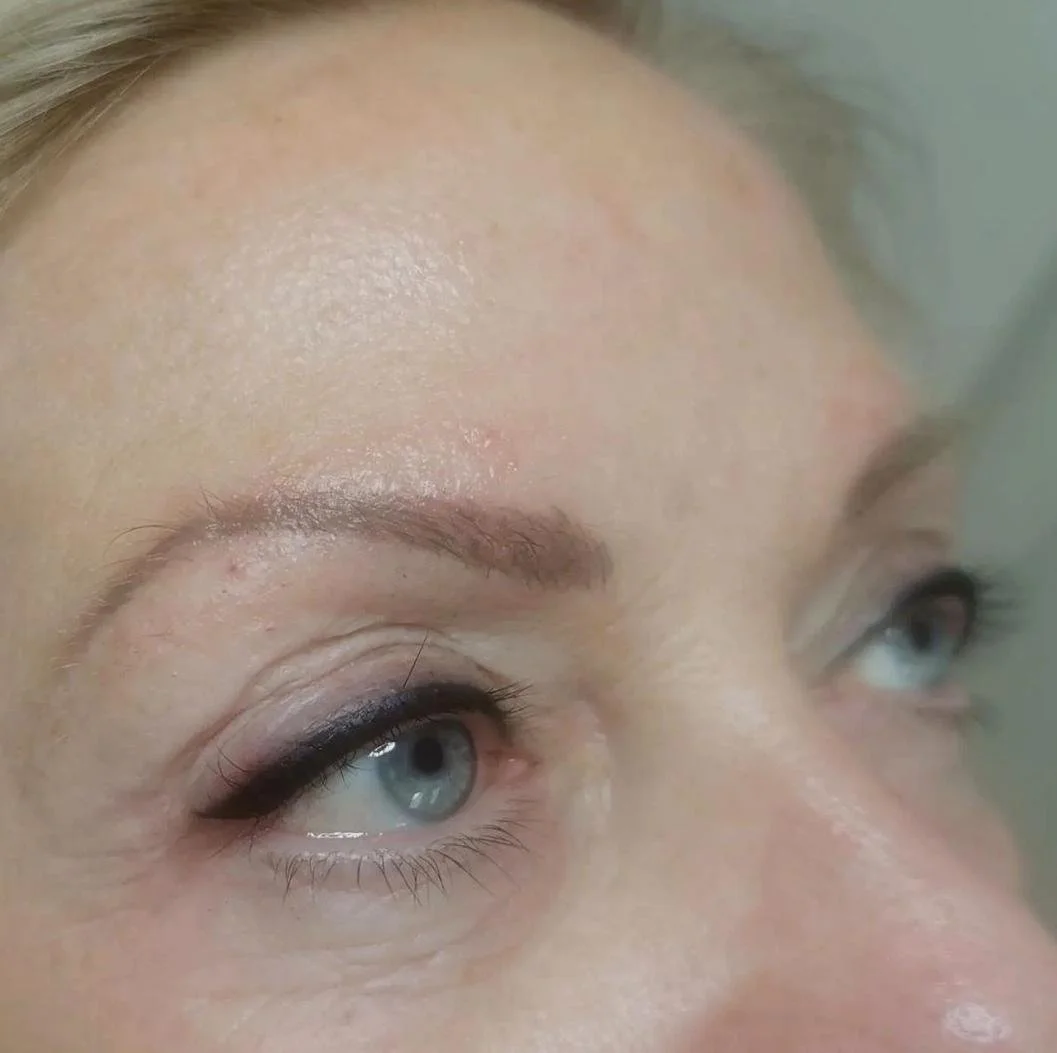 Close-up of a person's eye with light eyebrow and eyeliner.