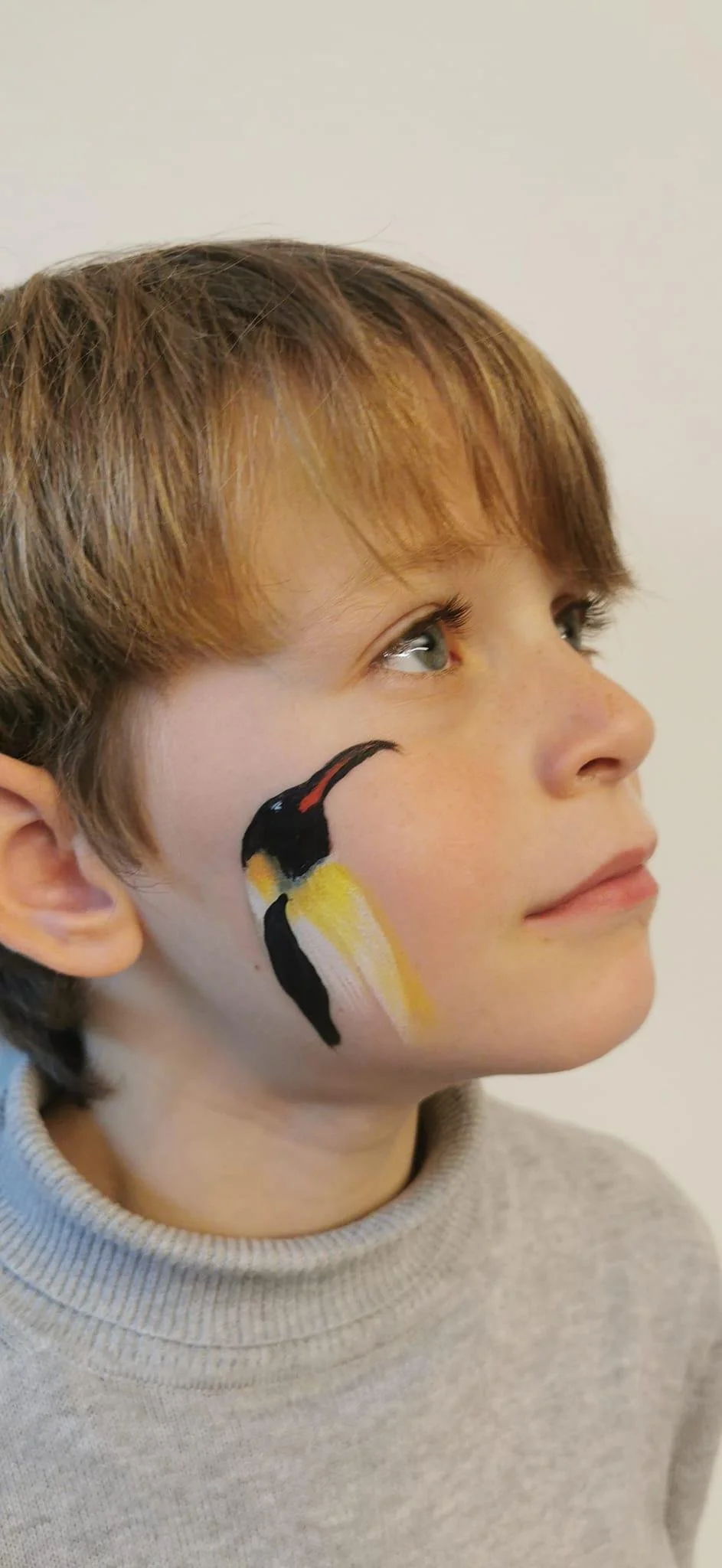 Child with penguin face paint on cheek