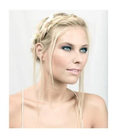 Woman with braided hairstyle and light makeup, gazing to the side against a white background.