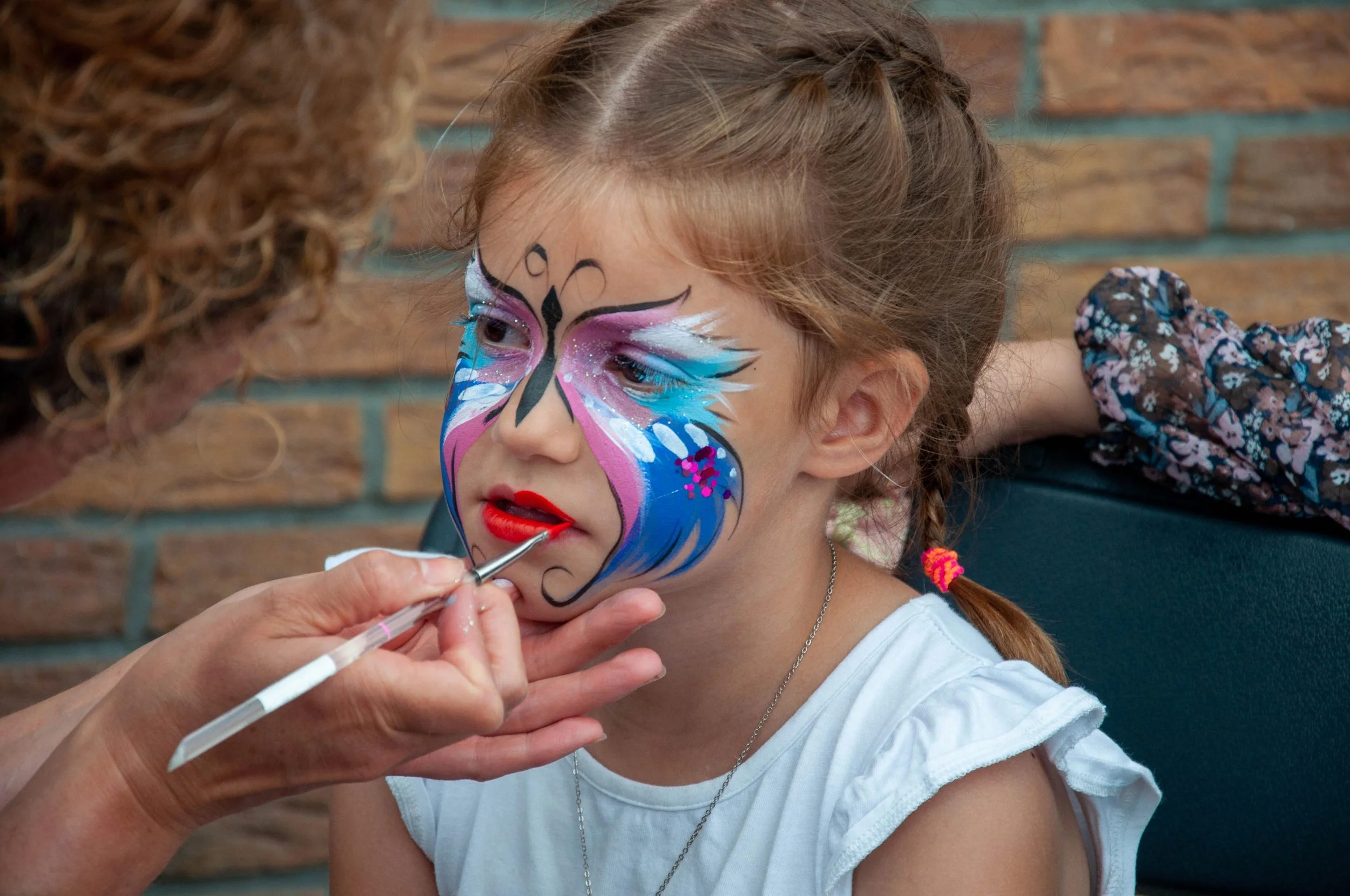 Young girl getting face paint with butterfly design