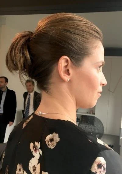 Woman with floral dress and brunette ponytail in indoor setting