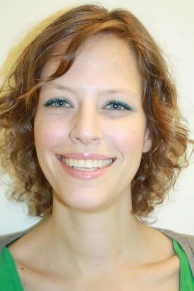 Smiling person with curly hair wearing green top