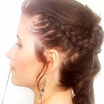 Side profile of woman with braided hairstyle and dangling earrings