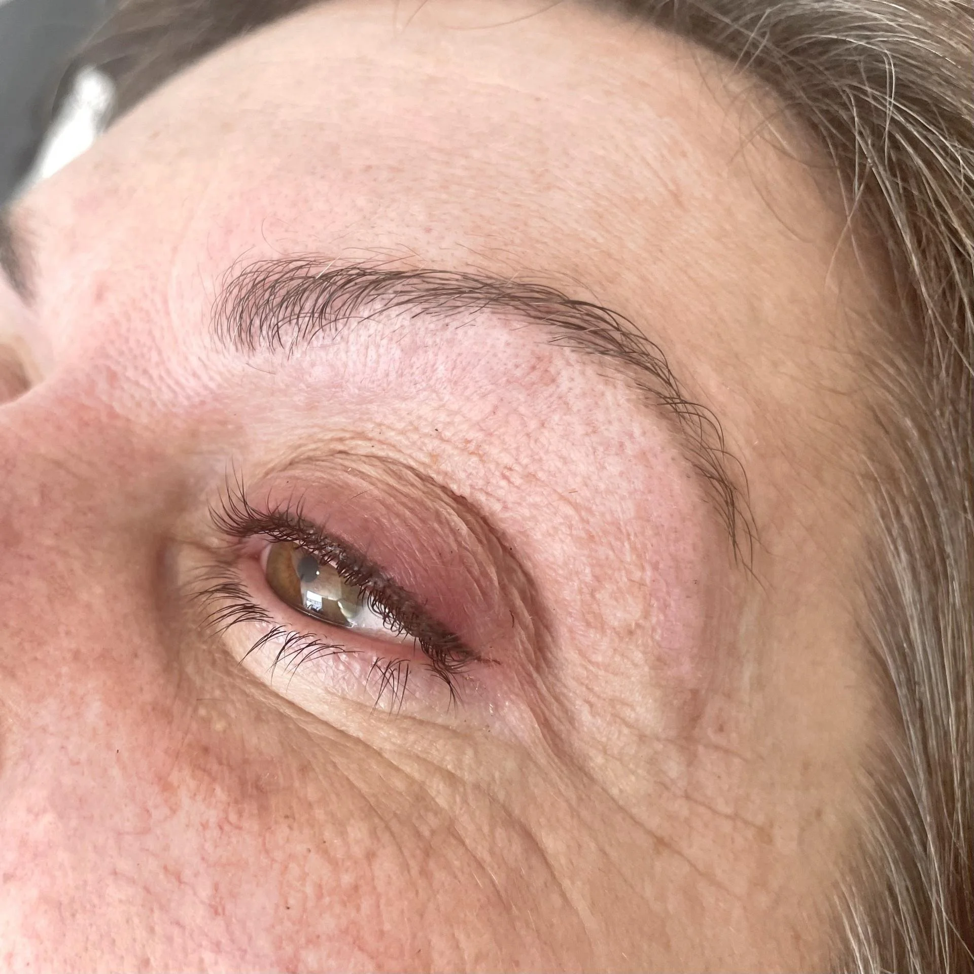 Close-up of a woman's eye with natural makeup and slight redness on the eyelid.