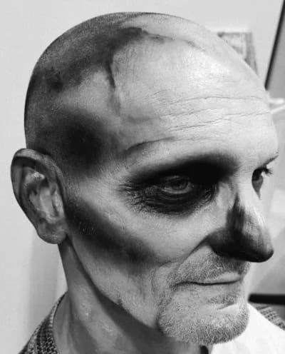 Person with skull-inspired face paint, dramatic nose contour in black and white.