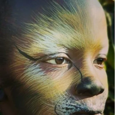 Person with face painted as a lion, showing detailed fur and whiskers design.