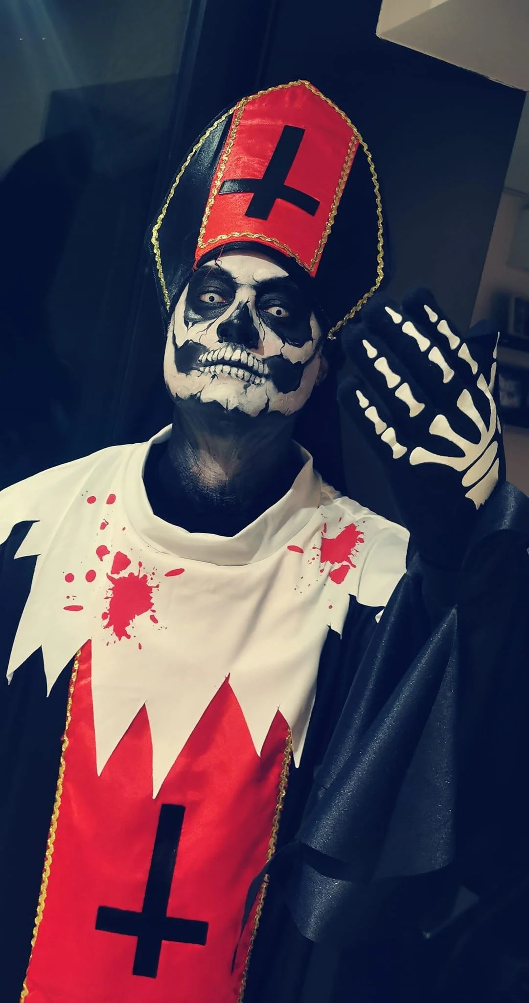 Person wearing a skeleton-themed costume with face paint and a red and black mitre.