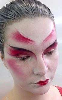 Close-up of a person with dramatic red and black face paint, resembling artistic or theatrical makeup.