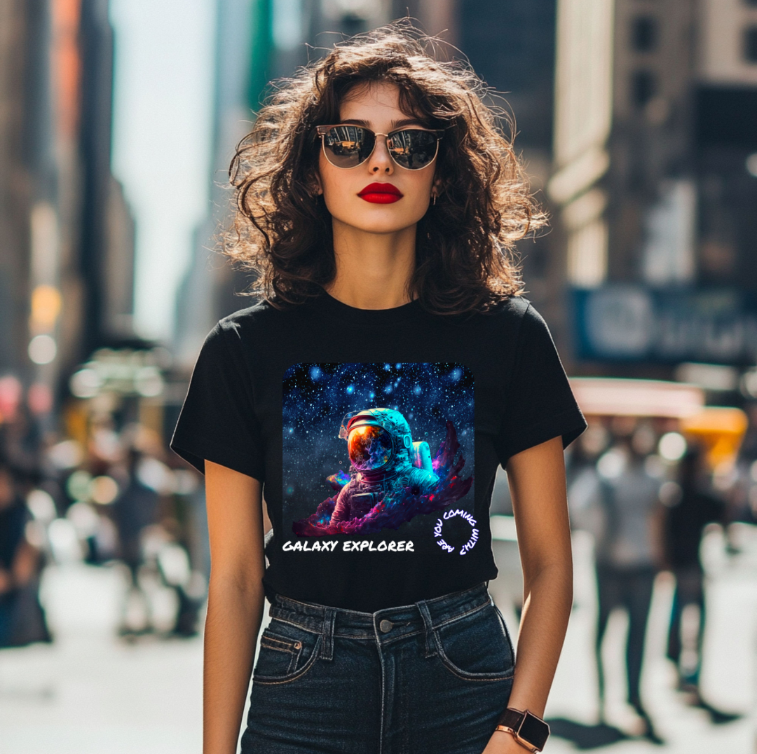 Young woman with curly hair wearing sunglasses, a black T-shirt with a galaxy explorer graphic, and dark jeans, standing in a busy city street.