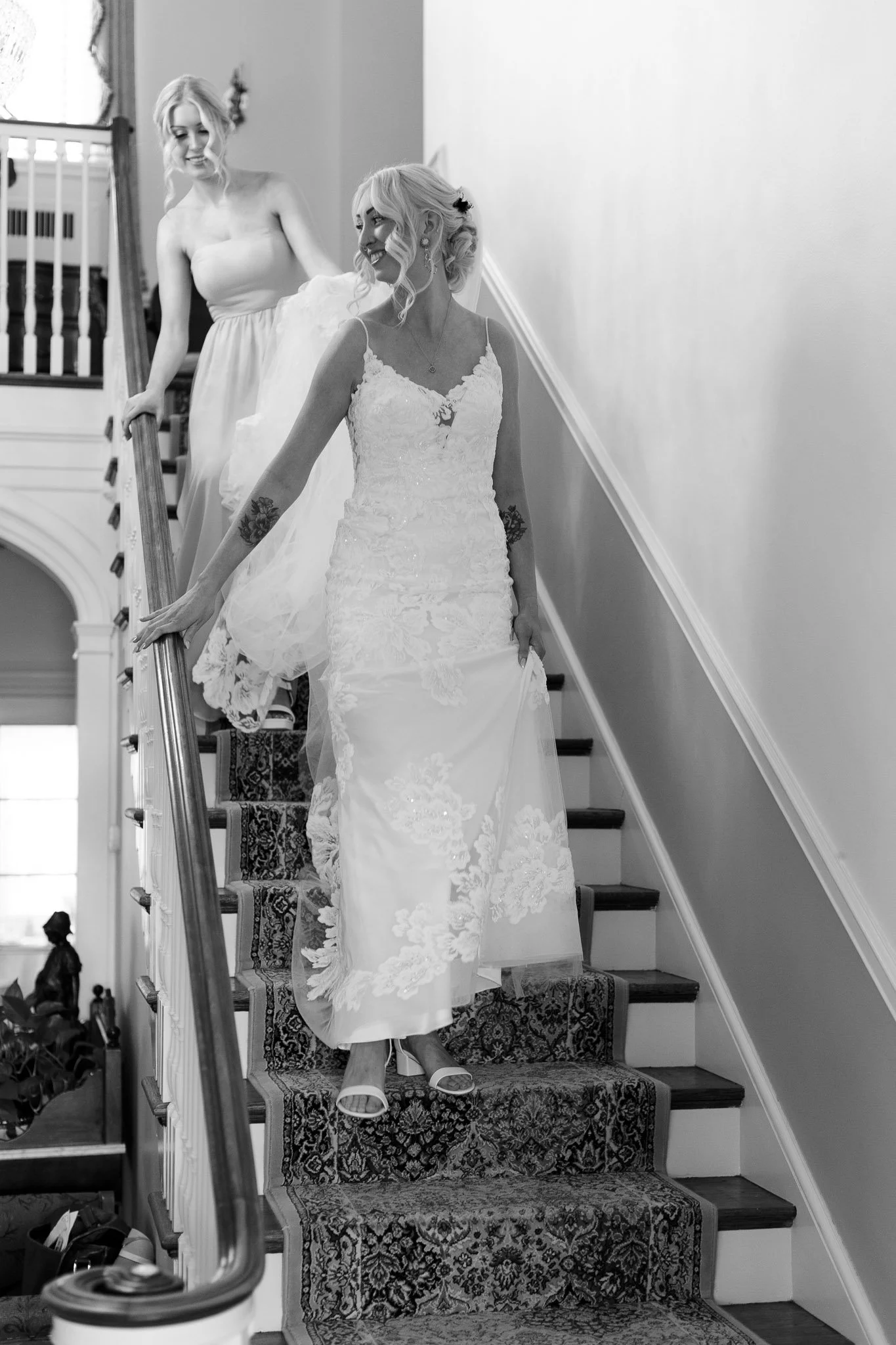 a black and white image of a bride and her bridesmaid descending the stairs at Drumore estate