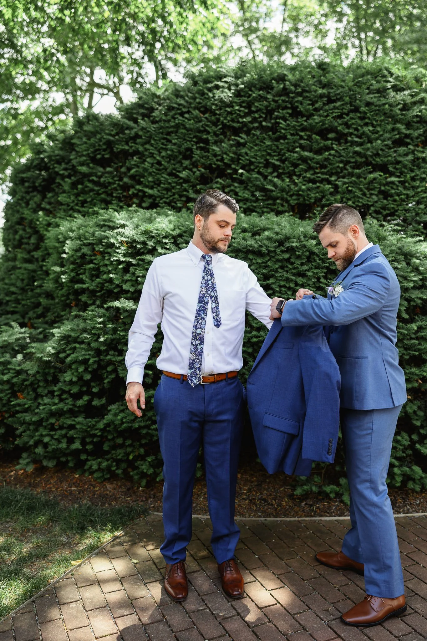 a wedding photography image of a groomsman helping the groom put on his jacket at the Drumore estate