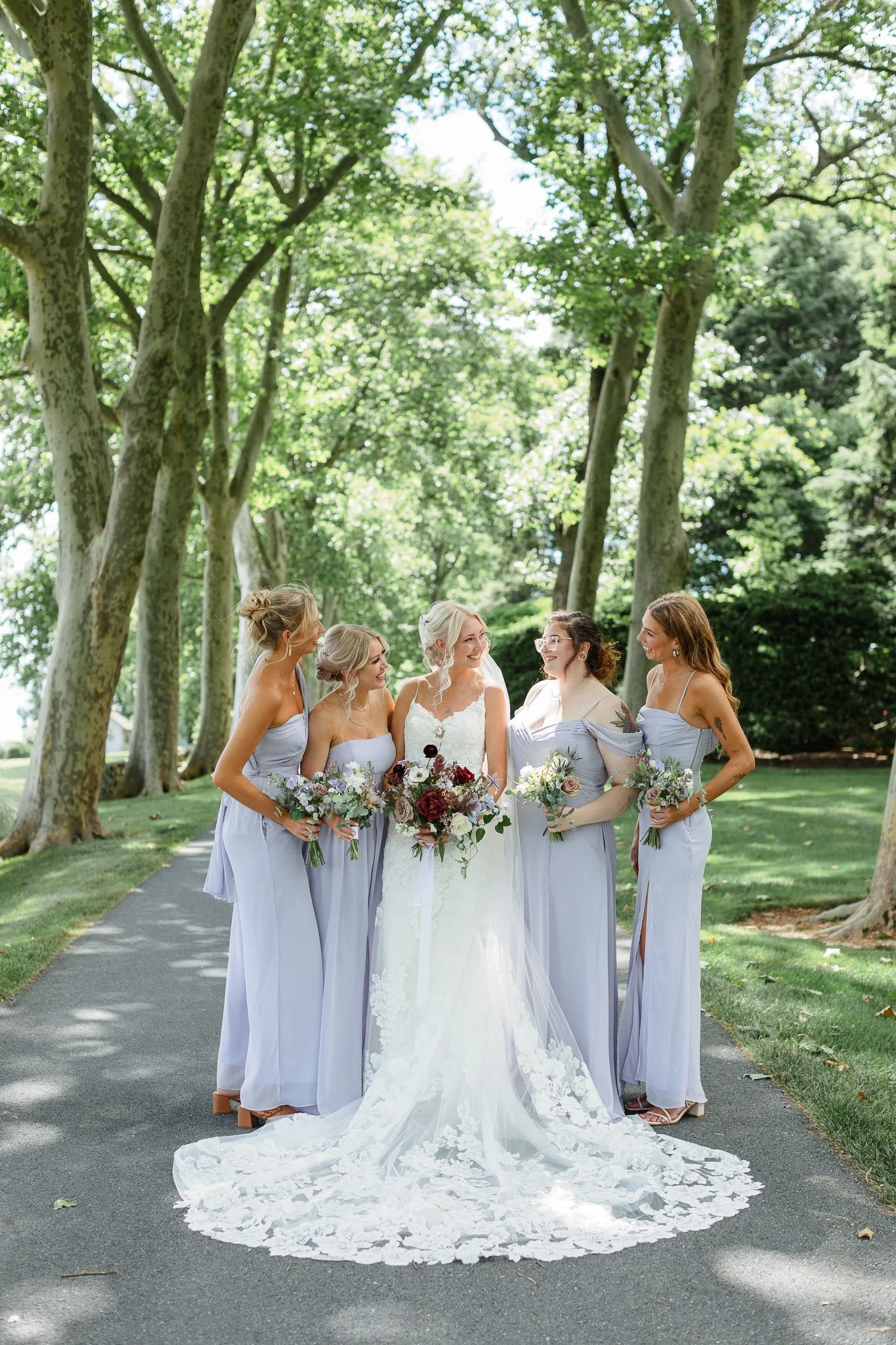 A wedding photographer captures the bridesmaids in their gowns alongside the bride’s lacy white dress.