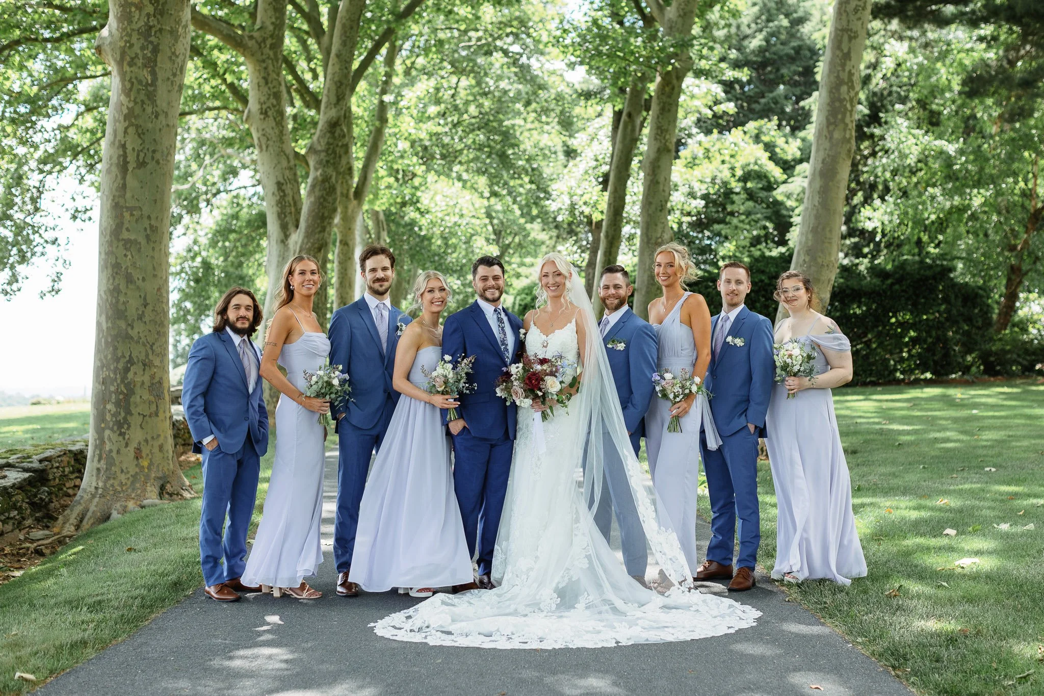 The bride and groom centered among their bridesmaids and groomsmen on the lawn of the Pequea venue.