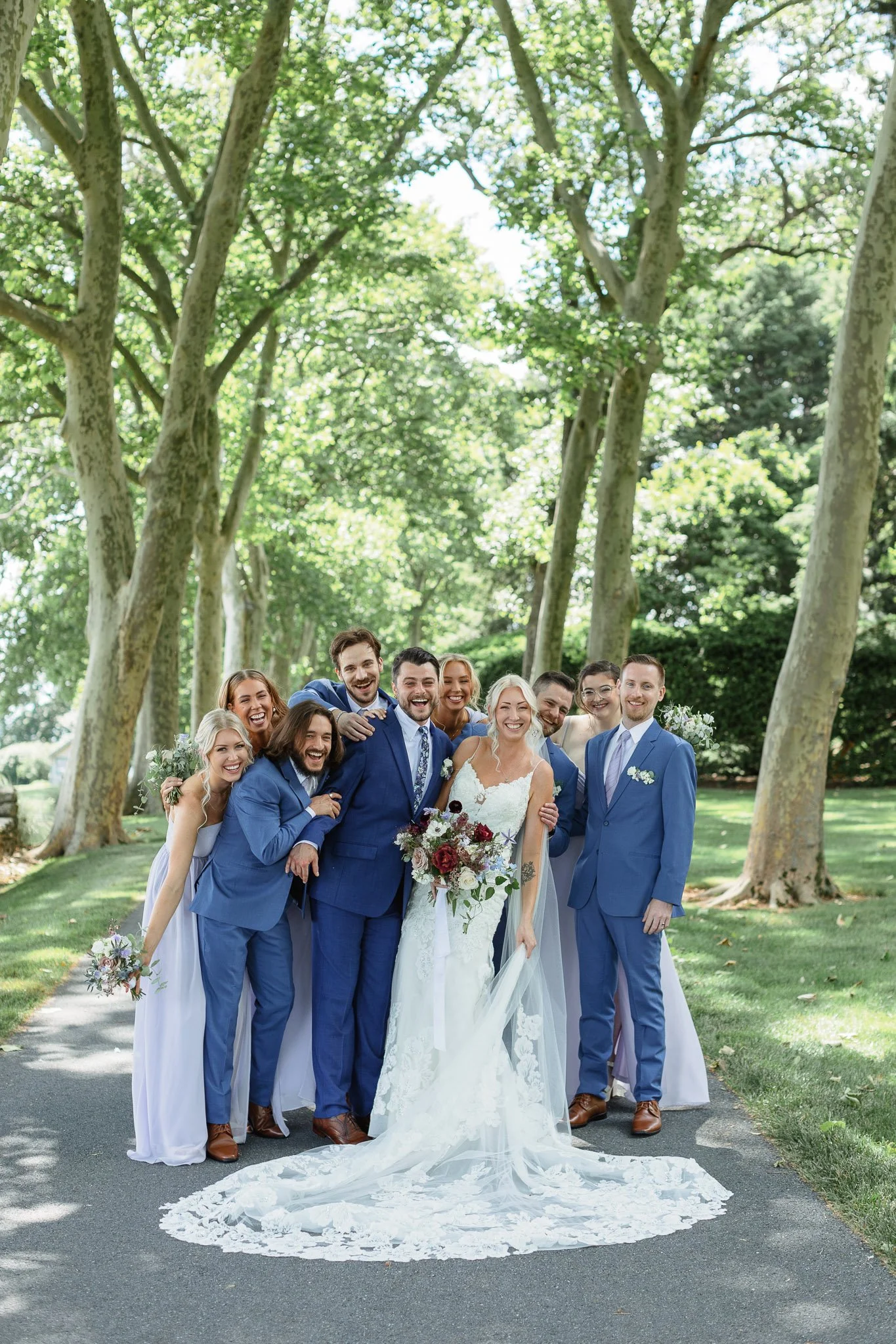 Formal portrait of the wedding party framed by sun soaked trees of Drumore Estate.