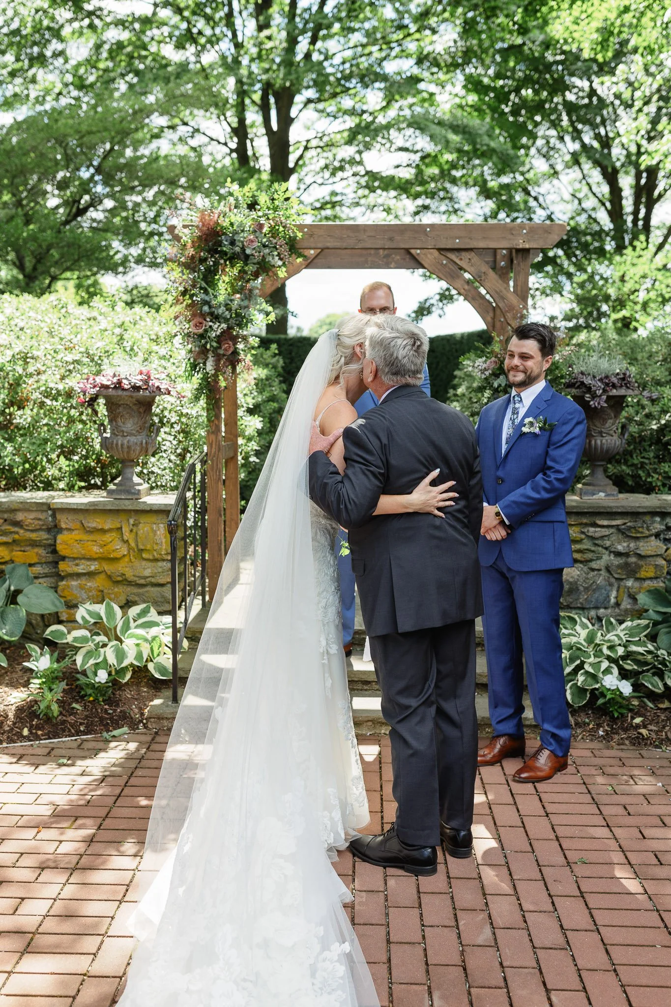 A wedding photographer captures the couple holding hands while exchanging vows in the open air of Pequea, PA.
