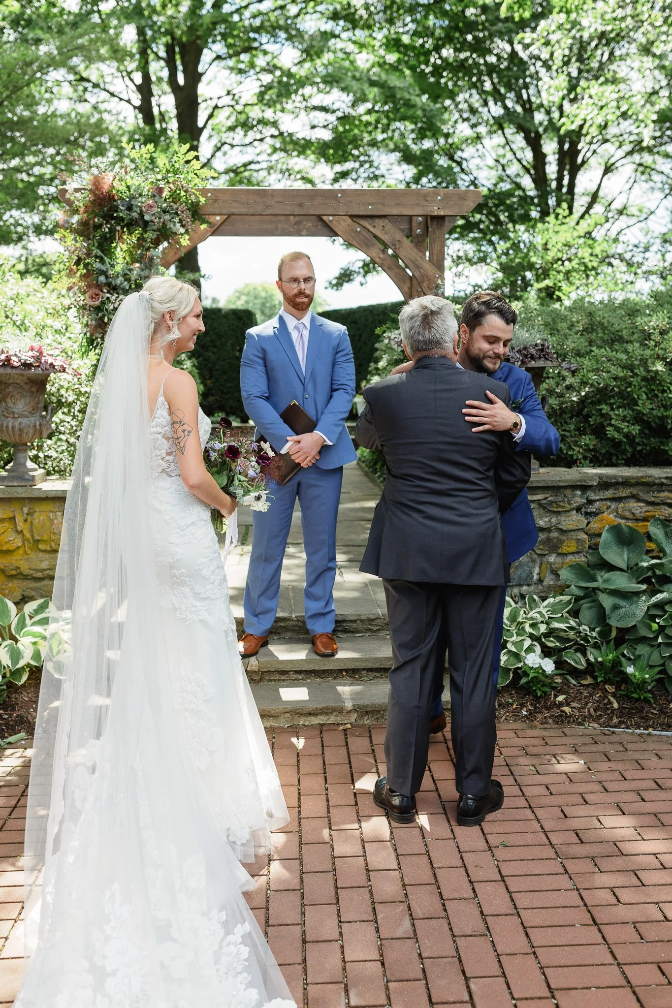 The bride and groom standing before the officiant, framed by the manicured hedges and stone features of Drumore Estate.