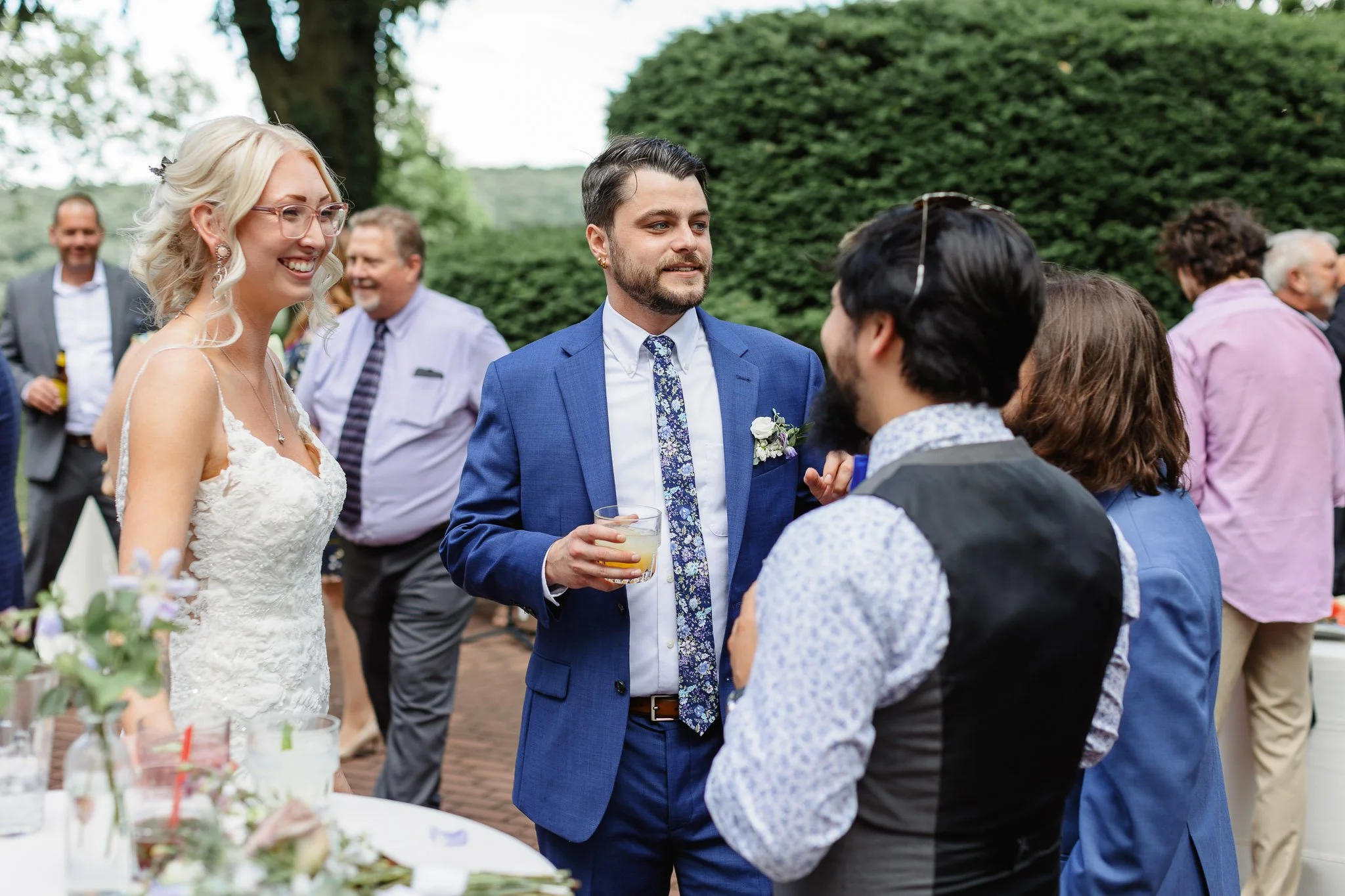 The bride in her lacy white dress chatting with friends on the brick patio at Drumore Estate.