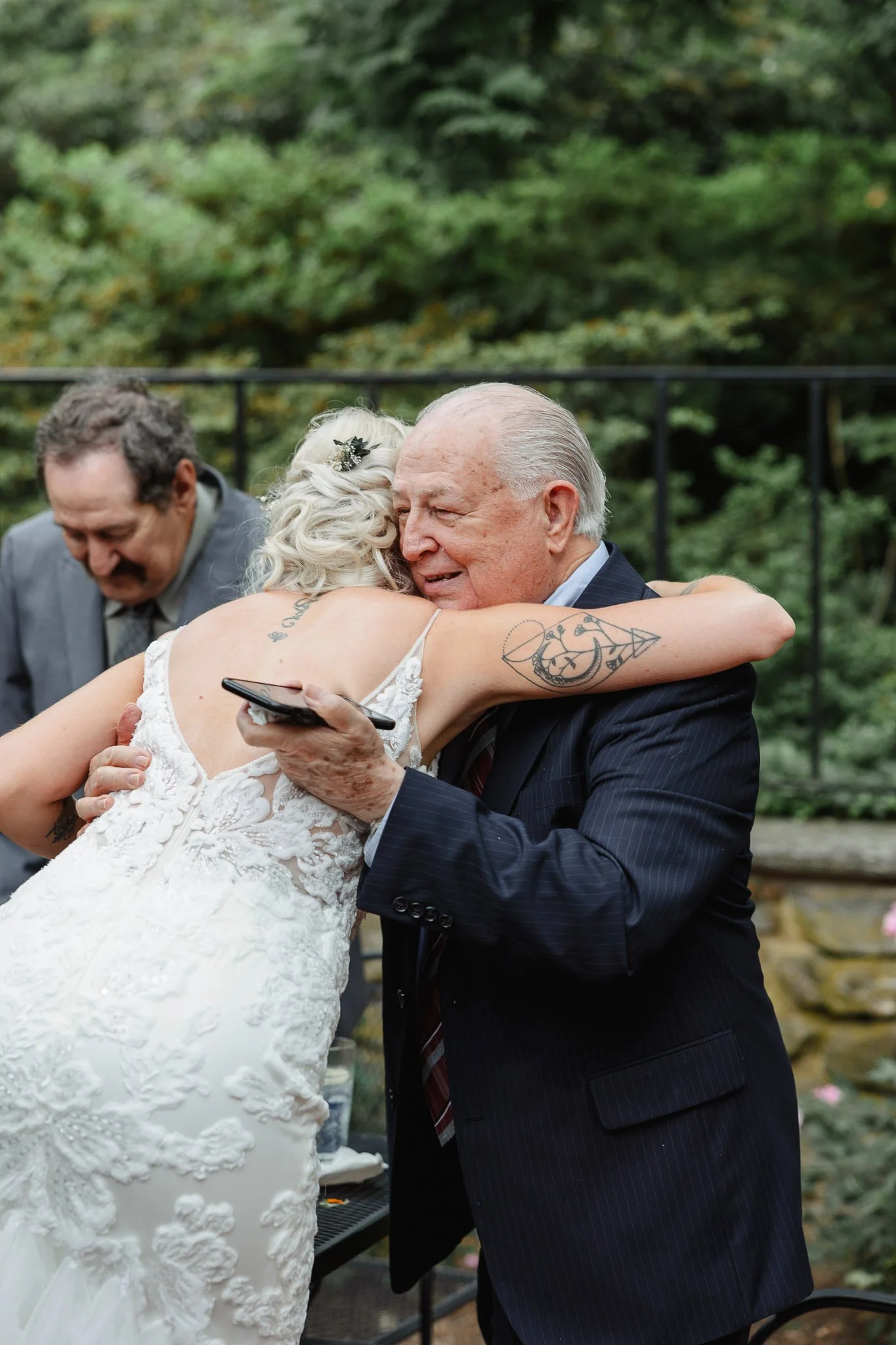 A wedding photographer captures the bride sharing a joyful embrace with a guest outside the venue.