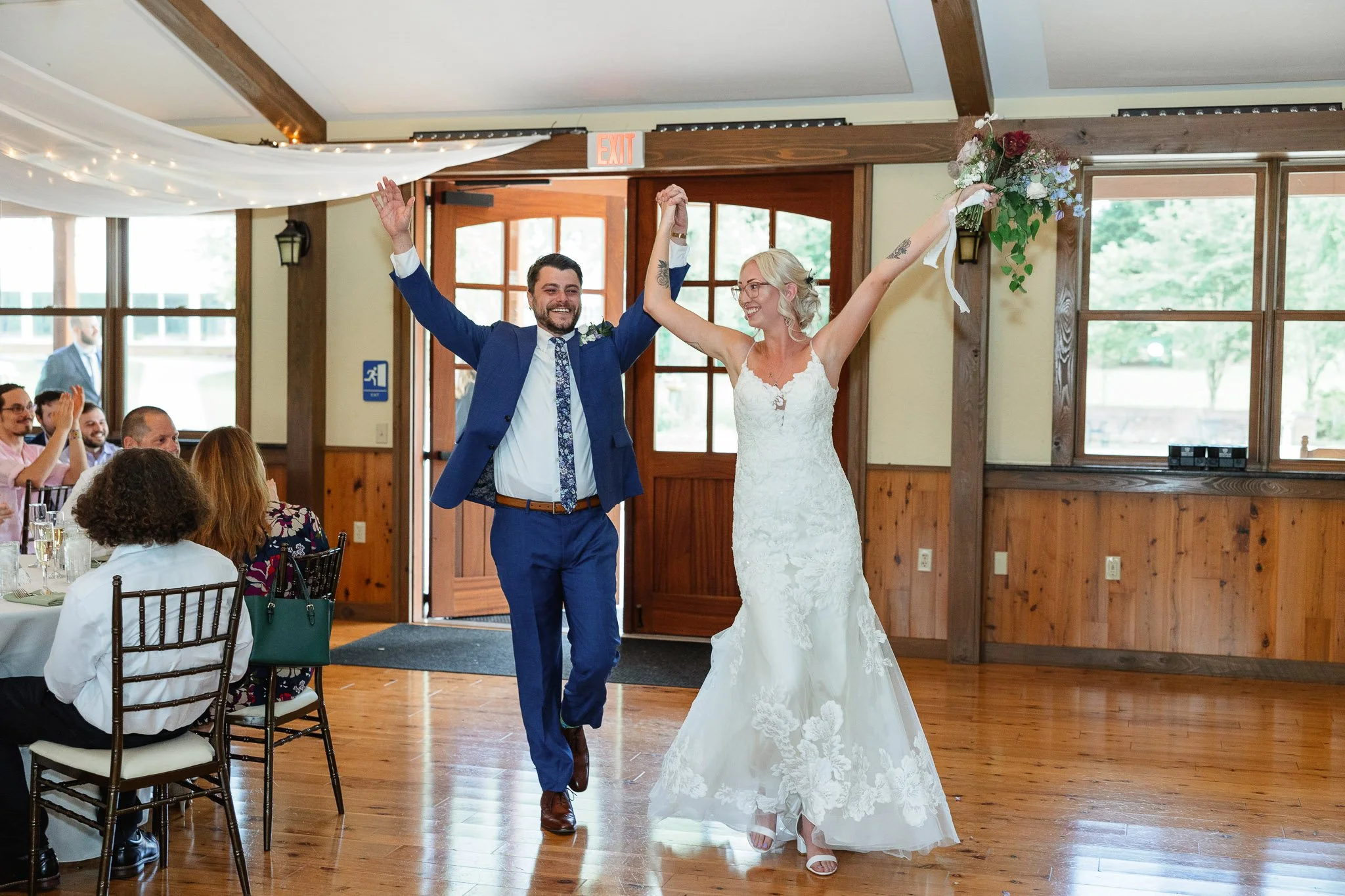 A high-energy wedding photo of the bride and groom entering the reception hall.