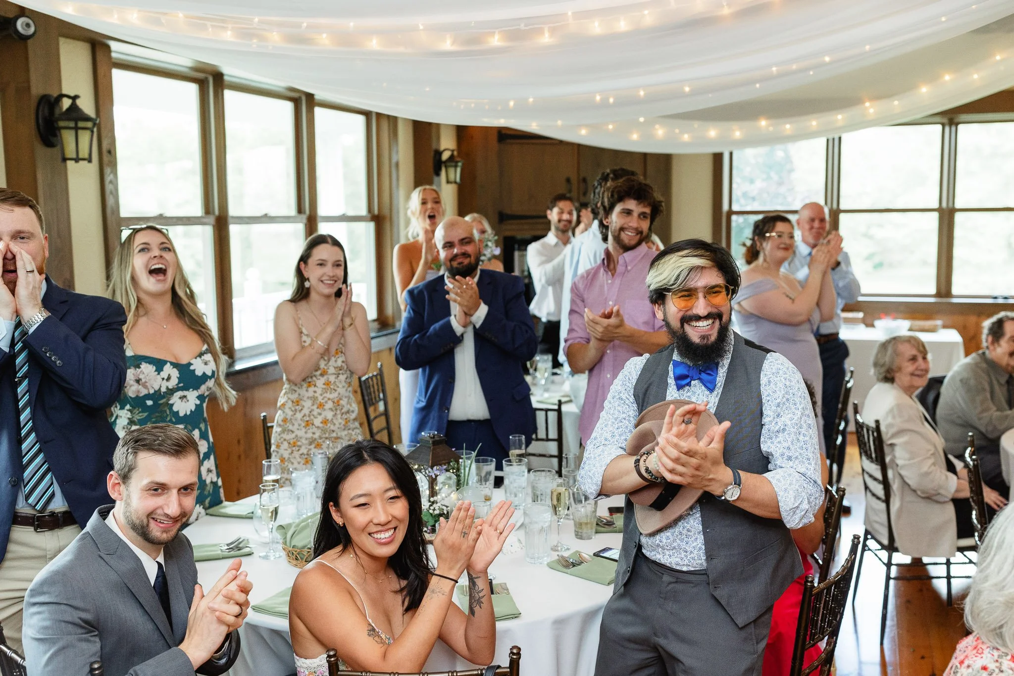 A wide wedding photo of a large group of guests cheering and clapping for the newlyweds on the dance floor at Drumore Estate.
