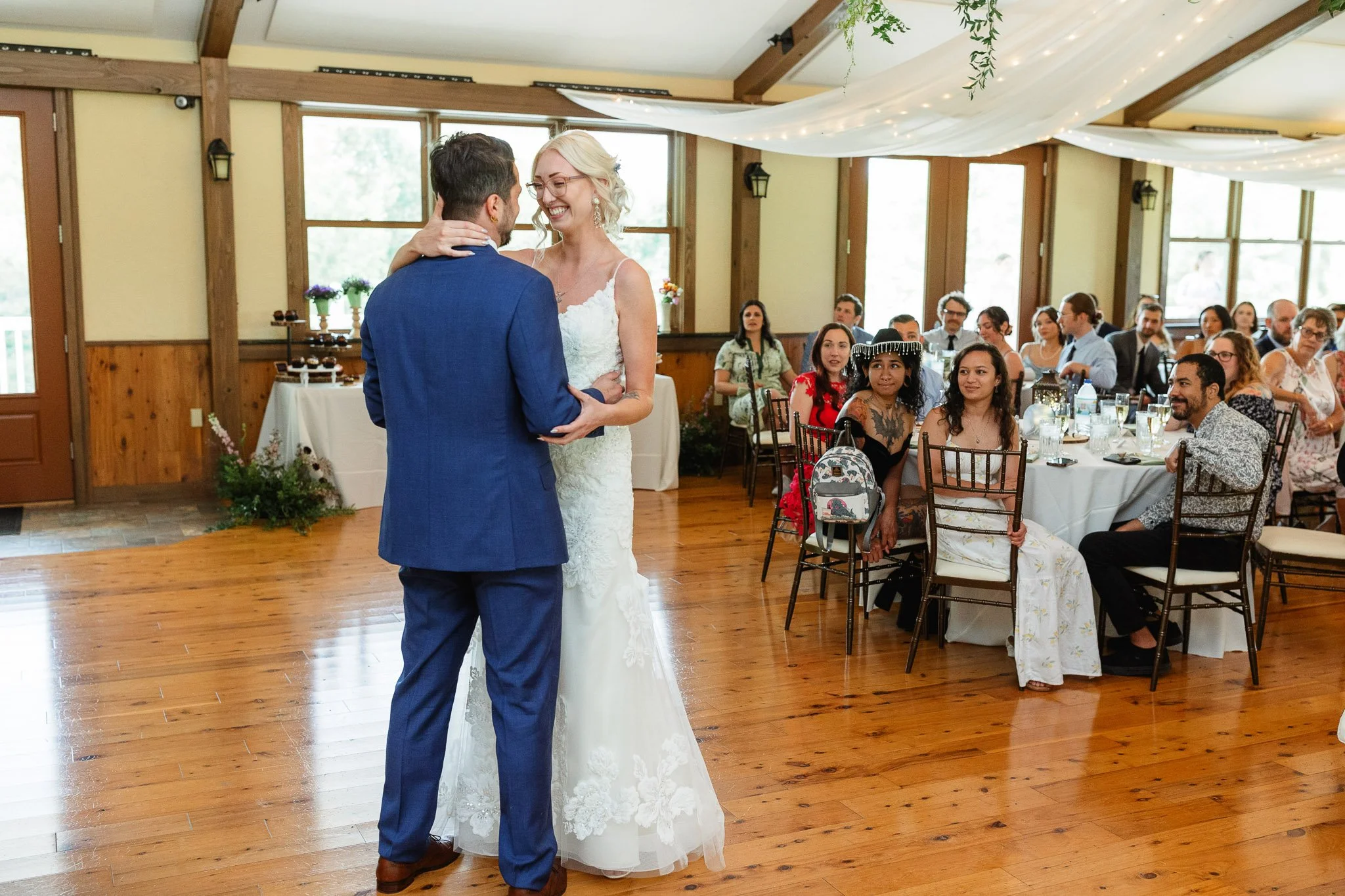 A romantic wedding photo of the bride and groom’s first dance, with the lacy white dress spinning across the floor under the warm reception lights.