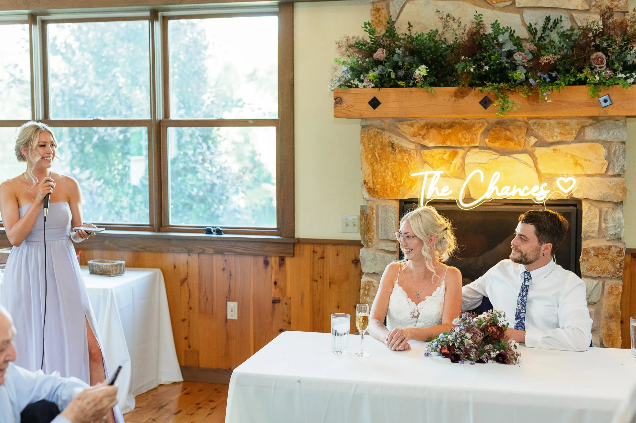 A candid wedding photo of the maid of honor giving a toast, capturing the bride and groom laughing at the head table at Drumore Estate.