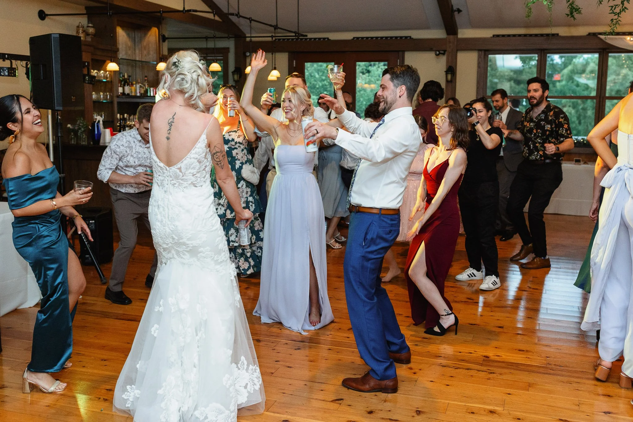 A high-energy wedding photo of guests dancing under the warm lights of the Drumore Estate reception hall.