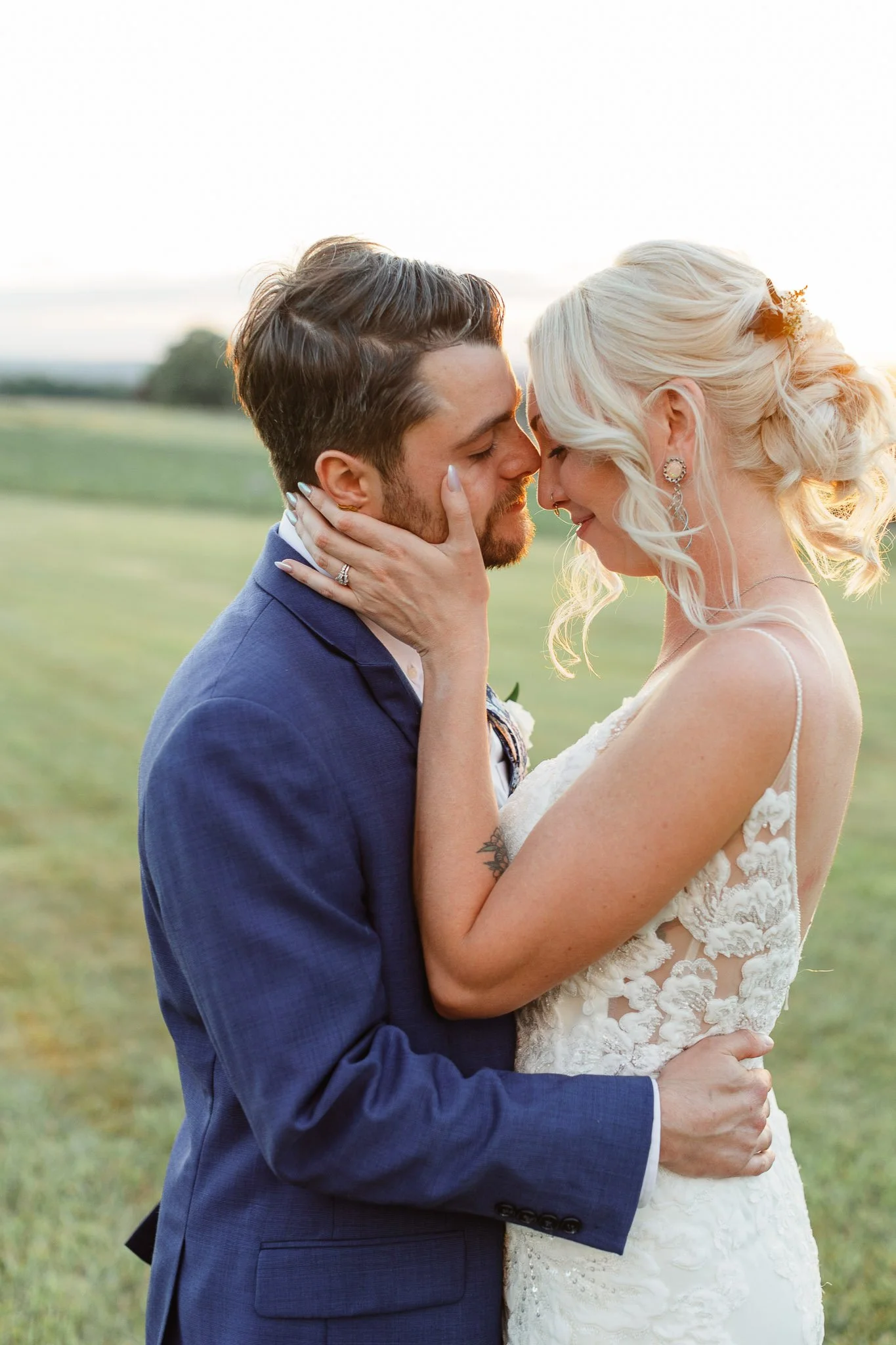 The couple sharing a quiet kiss with the soft, hazy glow of the setting sun creating a dreamlike atmosphere.