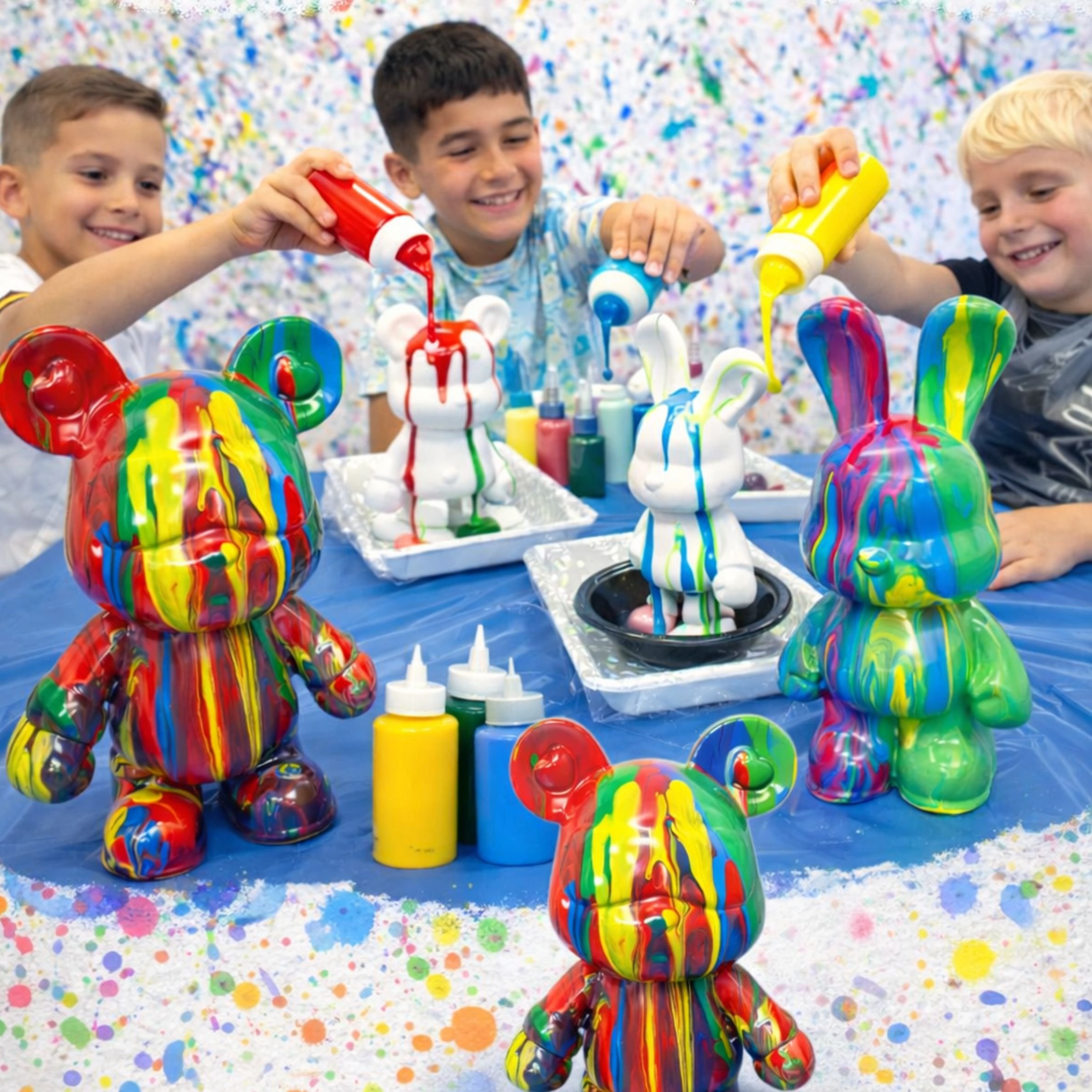Kids creating colorful paint pour art on bear and bunny figures.