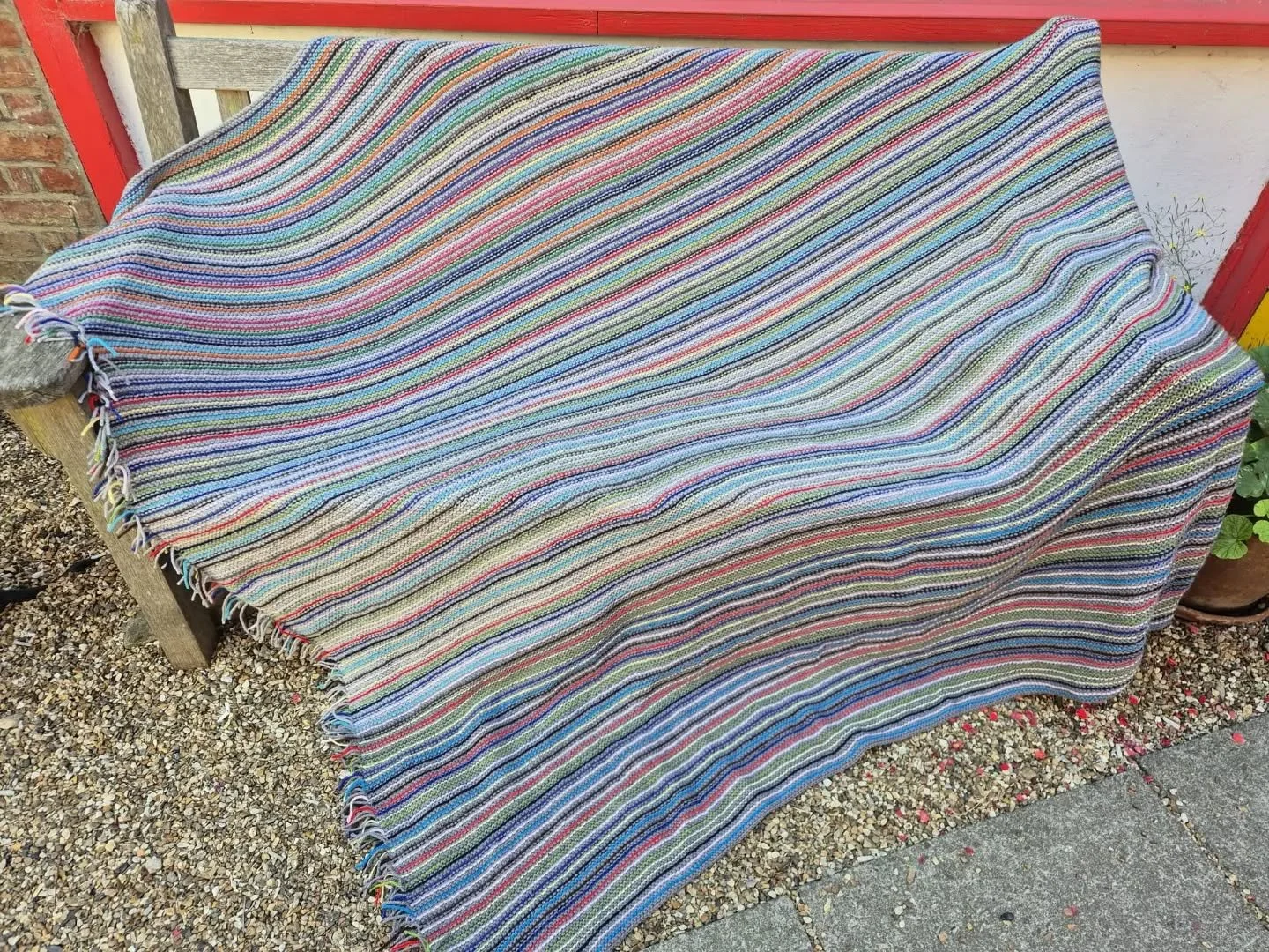 Sally in Tonbridge has sent us this excellent blanket. It's made in the style of one of our favourite stashbuster projects.  We love the colour choices and the occasional red stripe giving that extra pop.

Thank you, Sally. This is our Knit of the Da