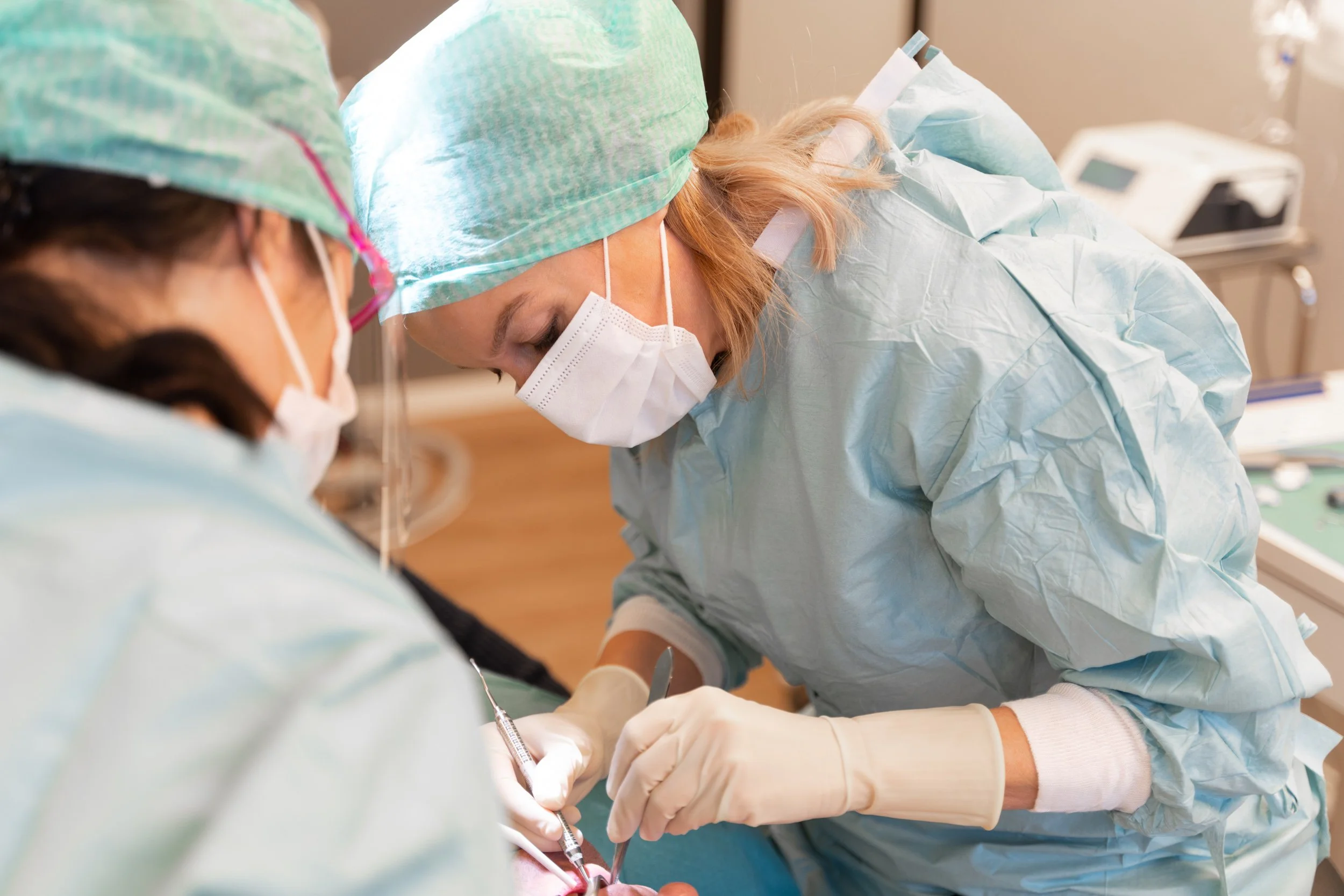 To kirurger i beskyttelsesutstyr utfører en operasjon på pasient.