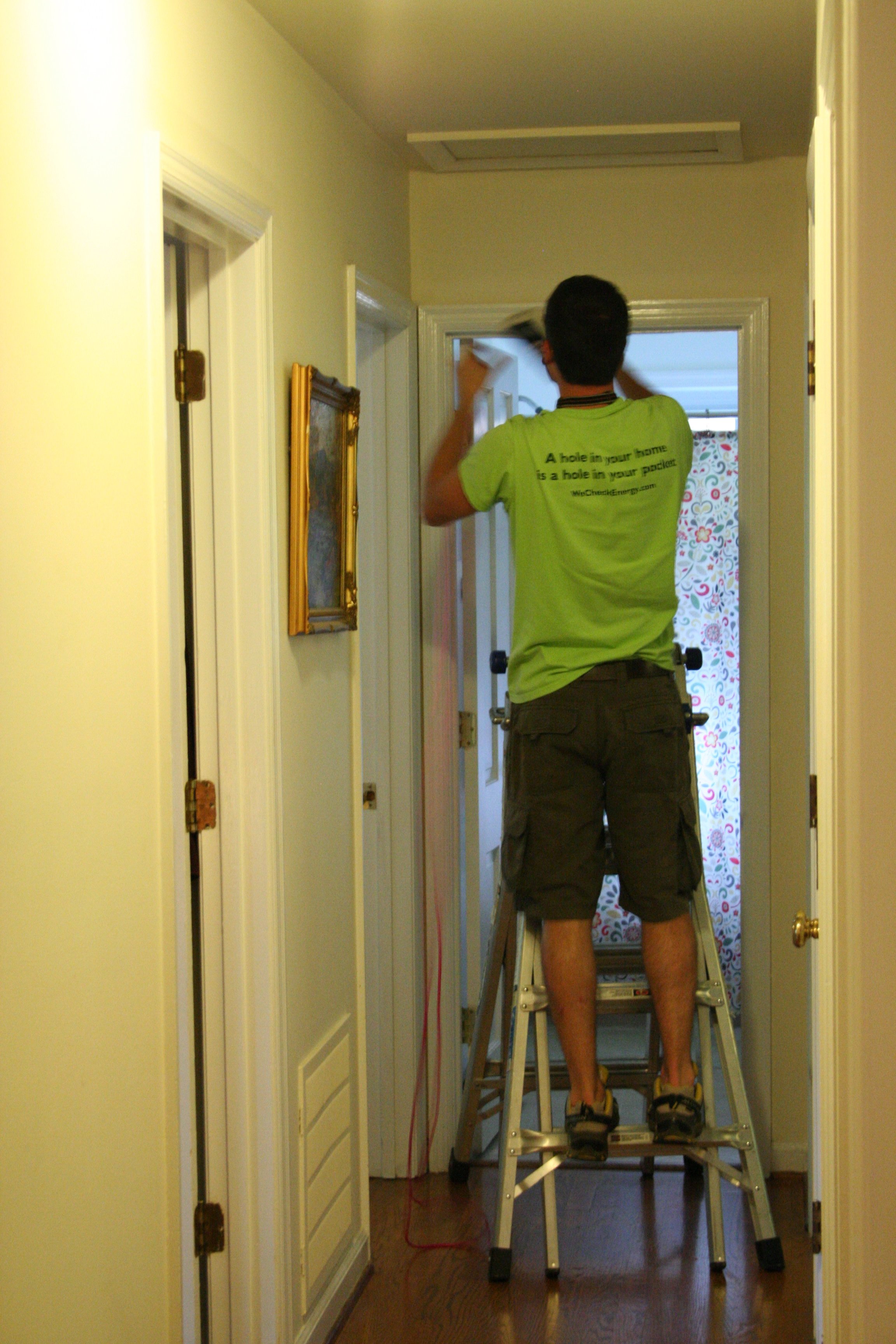 Energy auditor opening an attic access panel to inspect the attic for insulation, air leaks, and energy efficiency improvements, ensuring optimal home performance